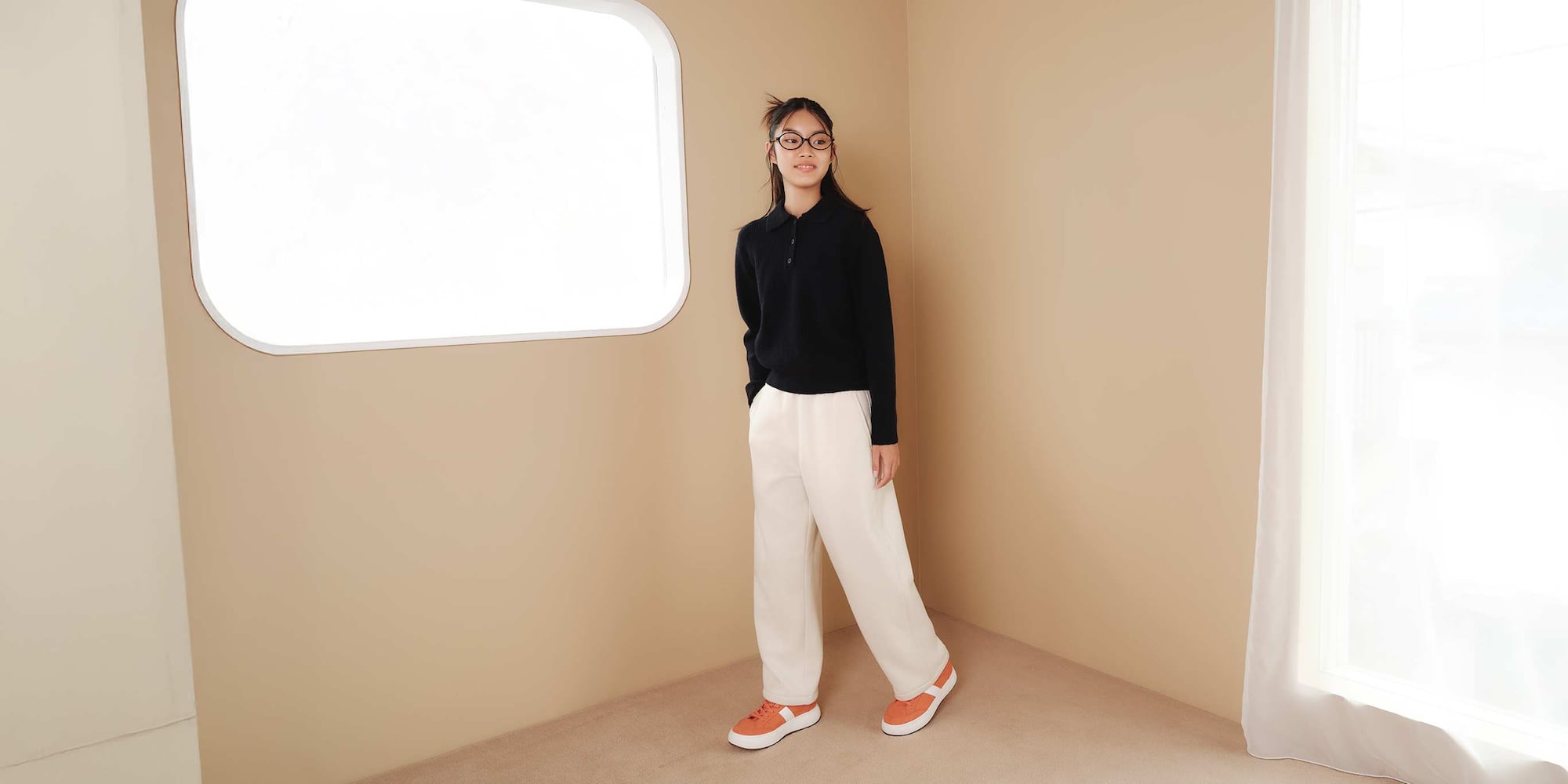 model wearing Pile Lined Sweat Wide Trousers in off white with a black knitted polo and orange trainers
