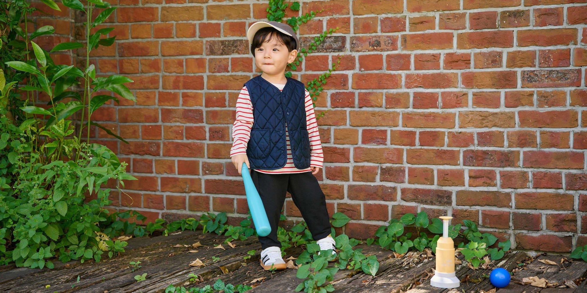 model wearing a navy quilted gilet with red and white striped long sleeved top, cap, and navy trousers