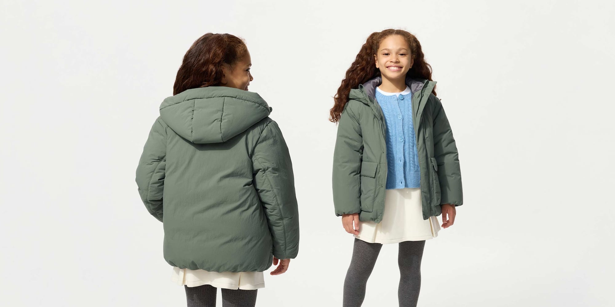 Bimba con il Piumino Piume Ibride con Cappuccio verde abbinato ad un cardigan azzurro e a una gonna a pieghe bianca