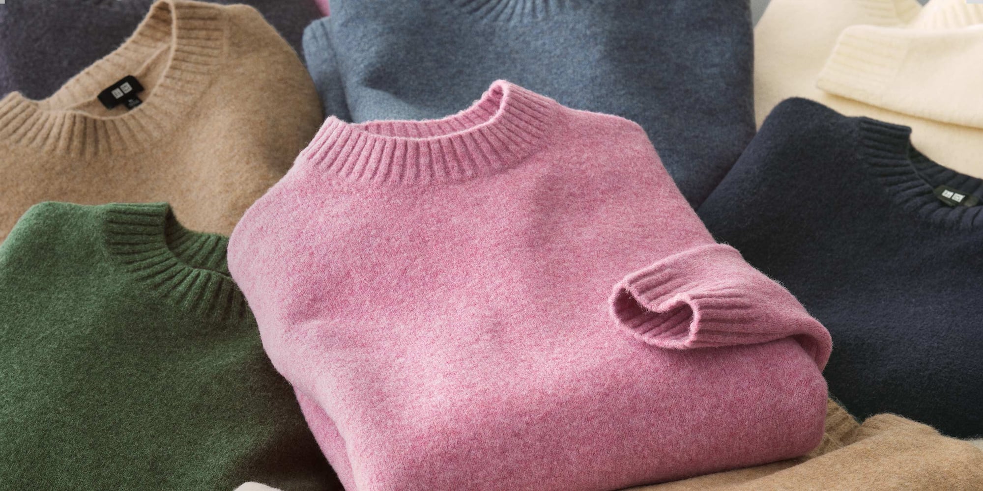 a close-up shot of a pile of Souffle Knit jumpers in grey, blue, beige, green, pink and cream