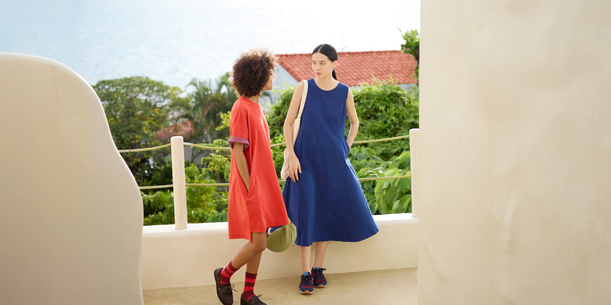 two models wearing UNIQLO dresses with the sea in the background