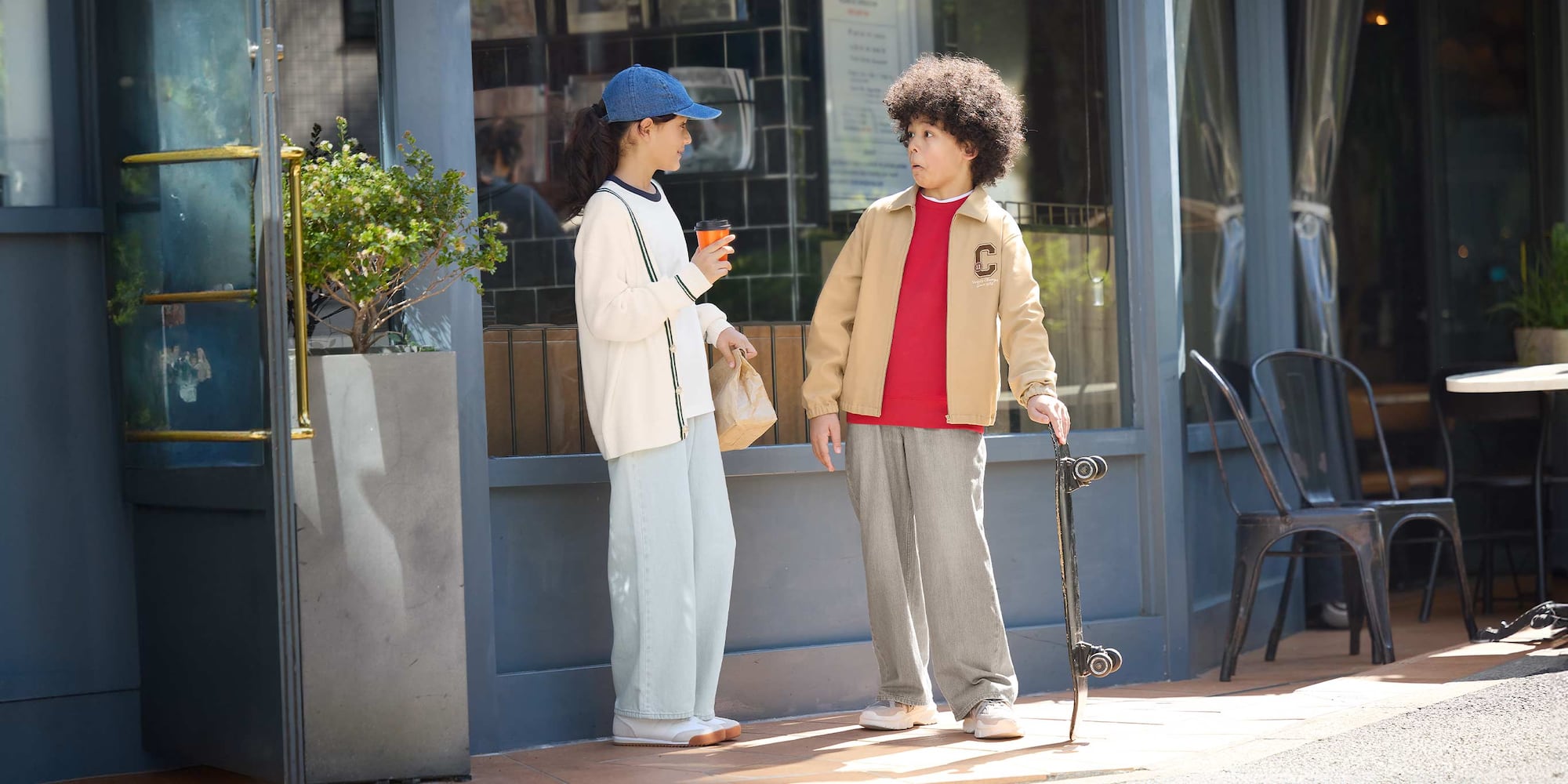 two models wearing UNIQLO jeans while standing outside a café