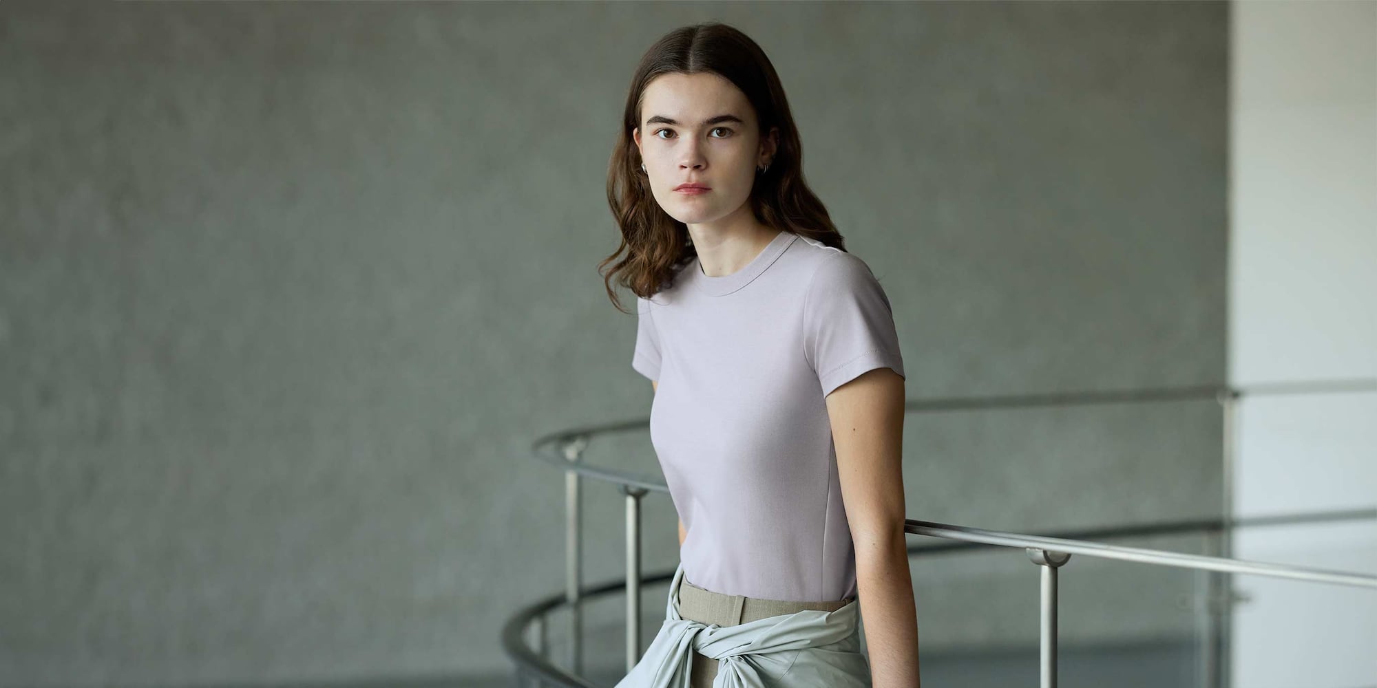 model wearing Crew Neck T-Shirt in light purple with beige trousers and light grey jacket tied at the waist