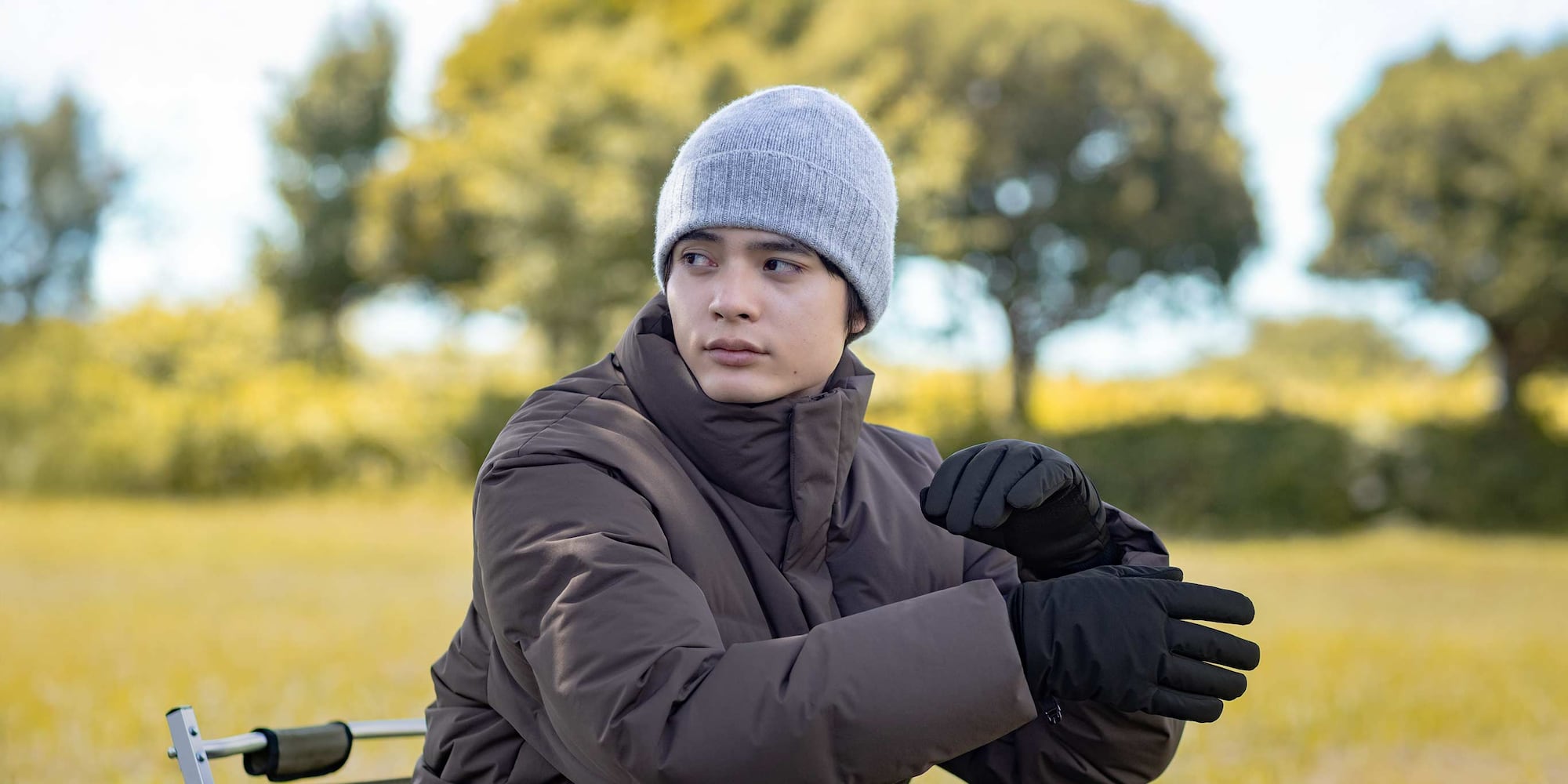 model wearing 100% Cashmere beanie in light grey with a brown down jacket and black gloves