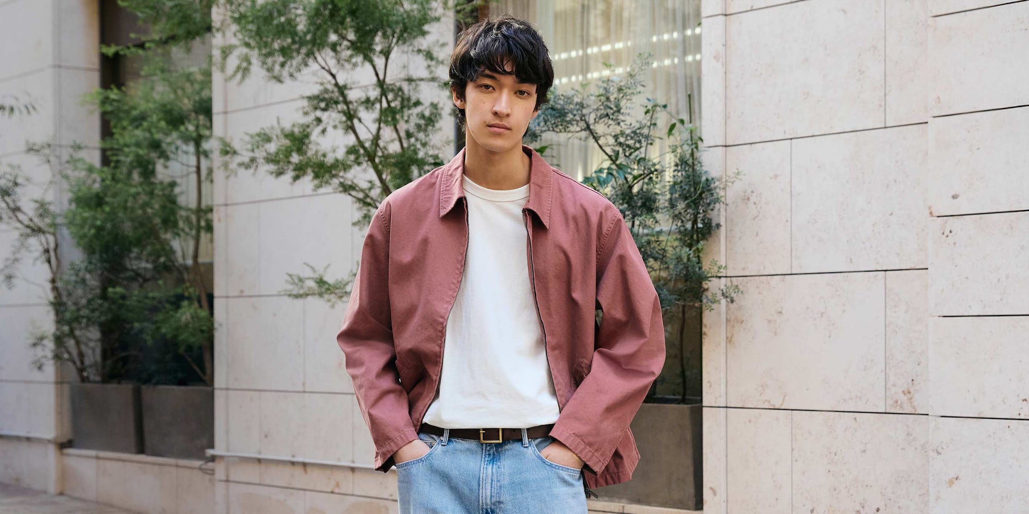 model wearing dark pink zip-up blouson over a white T-shirt and mid wash jeans