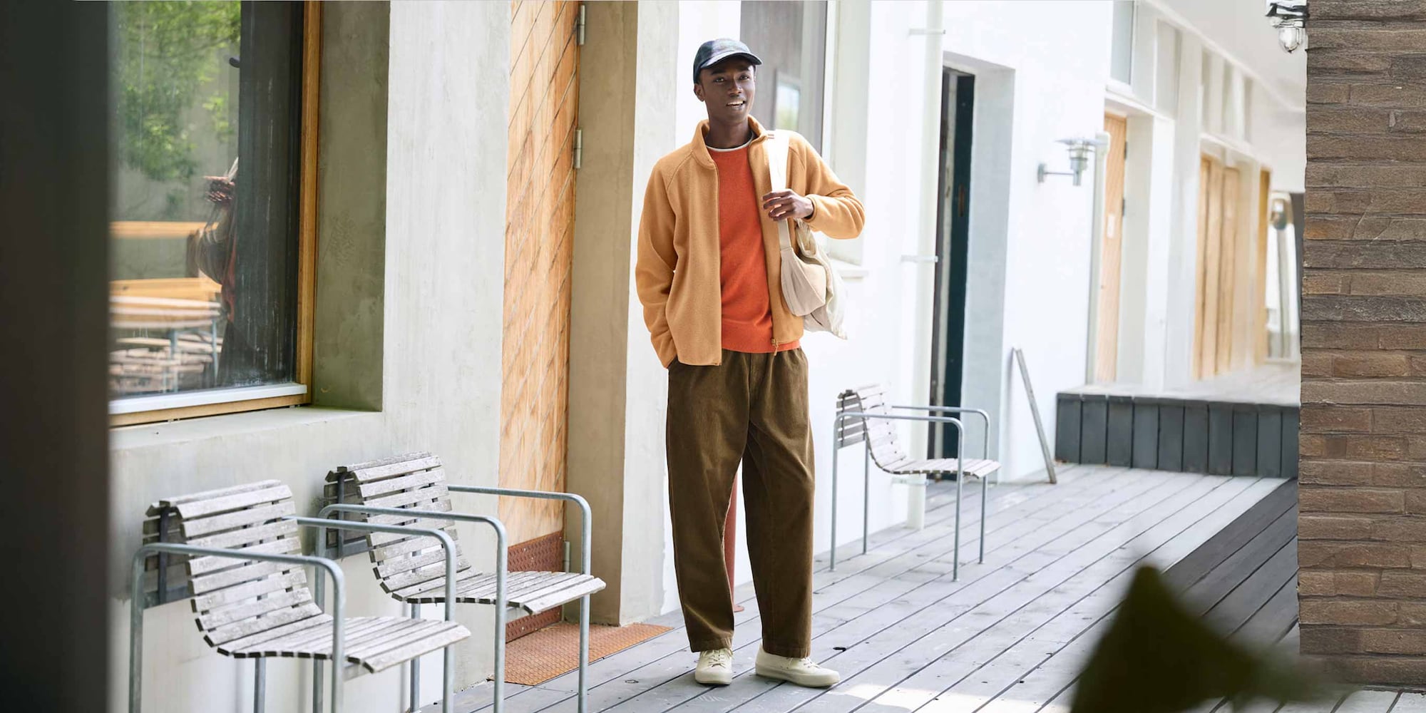 model wearing Corduroy Easy Ankle Trousers in brown with an orange knit and fleece and off white shoes and bag