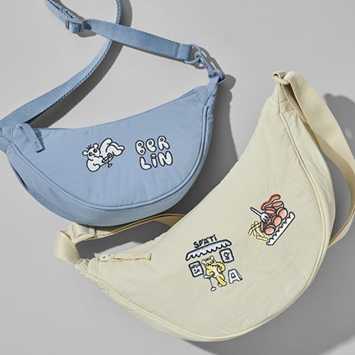 two round mini shoulder bags with embroidery designs by Magda Janicka; one light blue with the word Berlin in all caps and a bear drinking a martini, one in cream with a bear drinking a lemonade outside a Späti and Currywurst with chips