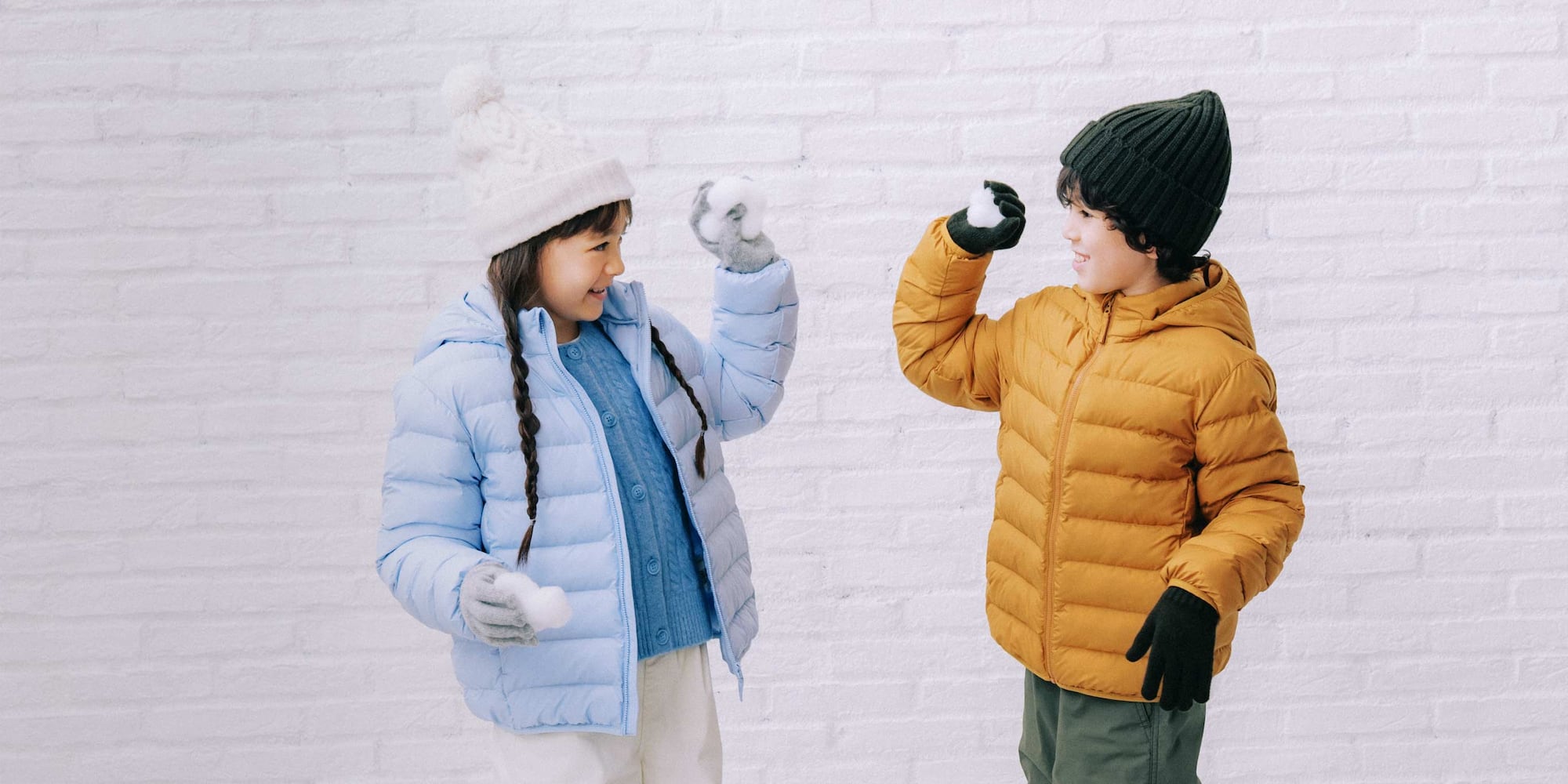 Bimbi con piumini e i berretti di UNIQLO giocano a palle di neve