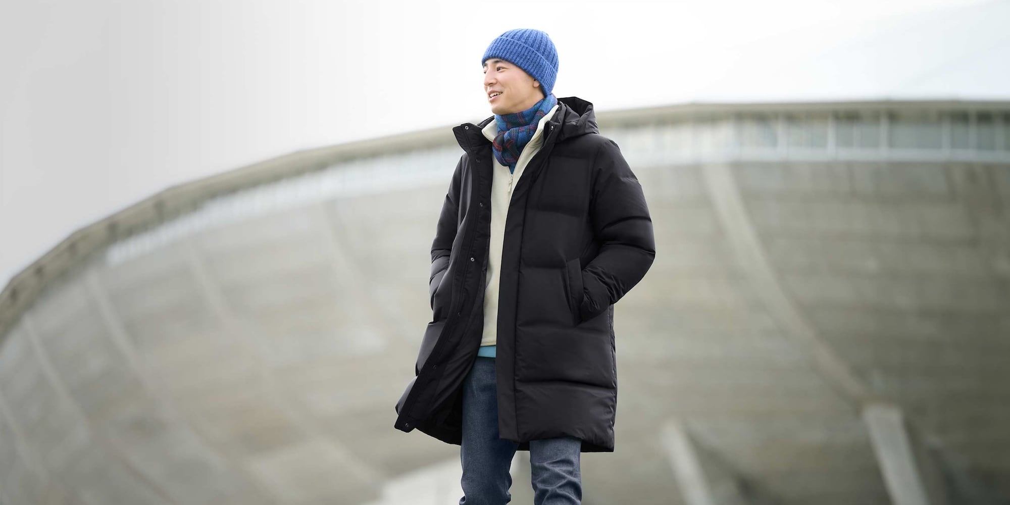 model wearing Seamless Down Coat in black over an off white fleece and jeans with a blue beanie and blue checked scarf