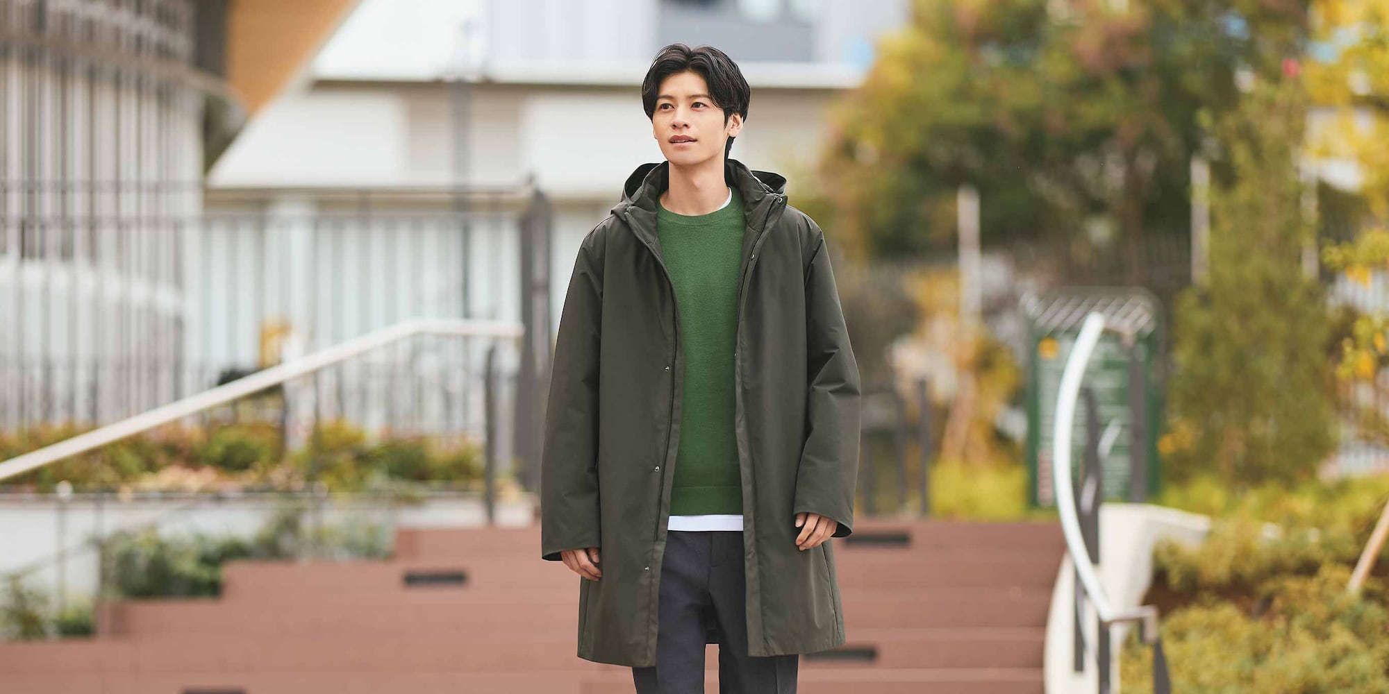 model wearing dark green Hybrid Down Recycled Coat over a green jumper and black trousers