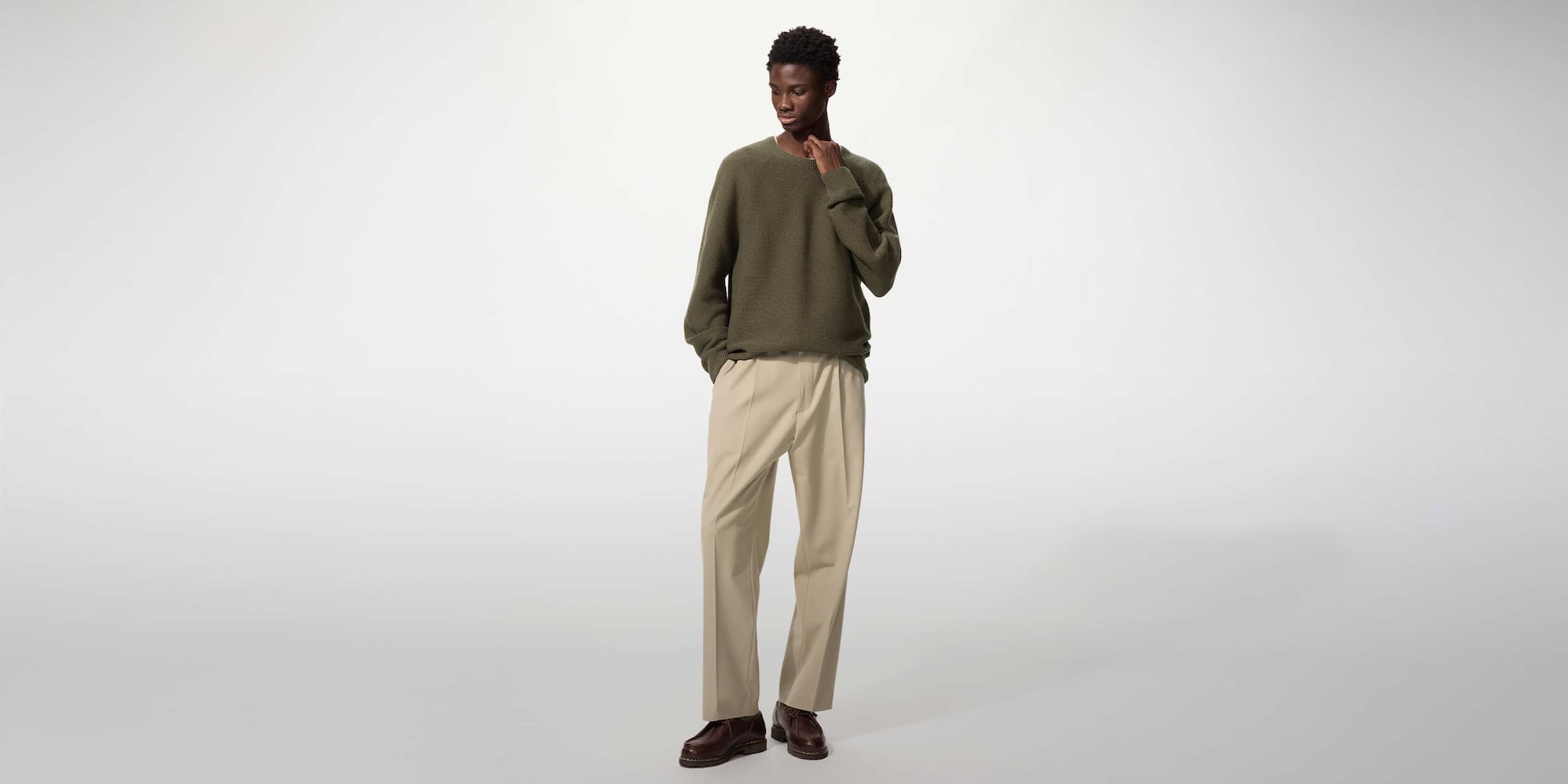 model wearing Pleated Wide Trousers in beige with a khaki knit and brown shoes