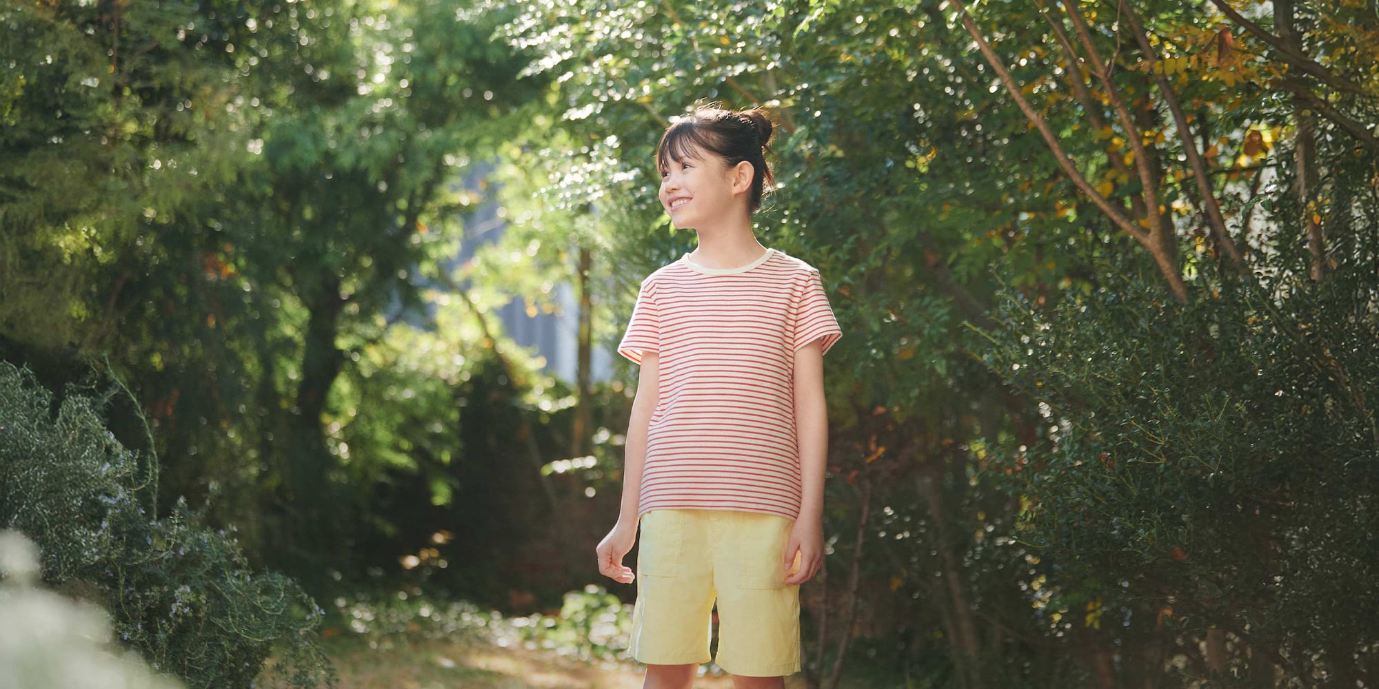 model wearing Ribbed T-Shirt in a red stripe while standing outside surrounded by trees