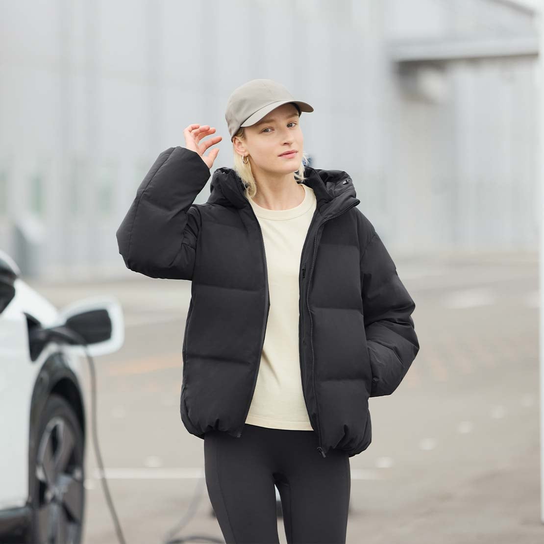 model wearing a black Seamless Down Parka, cream T-shirt, black leggings and stone colour cap