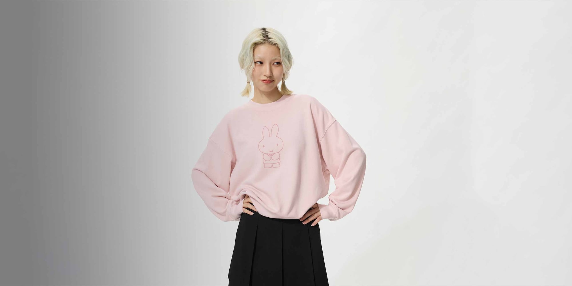 model wearing miffy in bloom UT Graphic Sweatshirt in pink with a black pleated skort