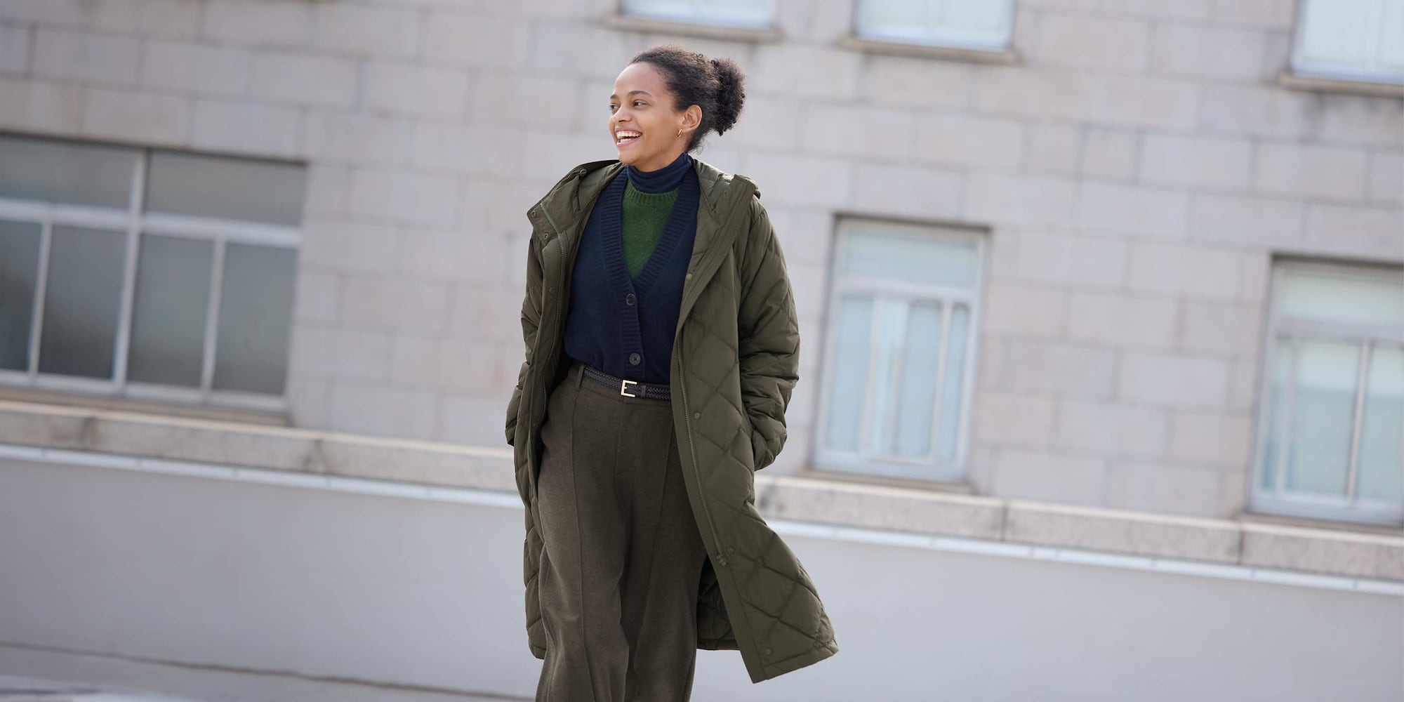 model wearing PUFFERTECH Long Coat in olive over a navy turtleneck, green crew neck jumper and navy cardigan with khaki trousers