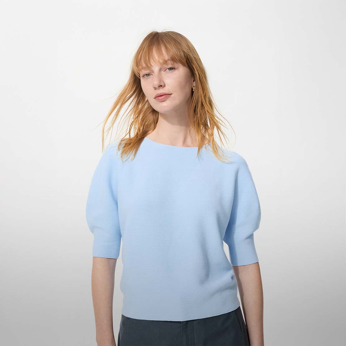 model wears a light blue cotton jumper with short sleeves in front of a white background