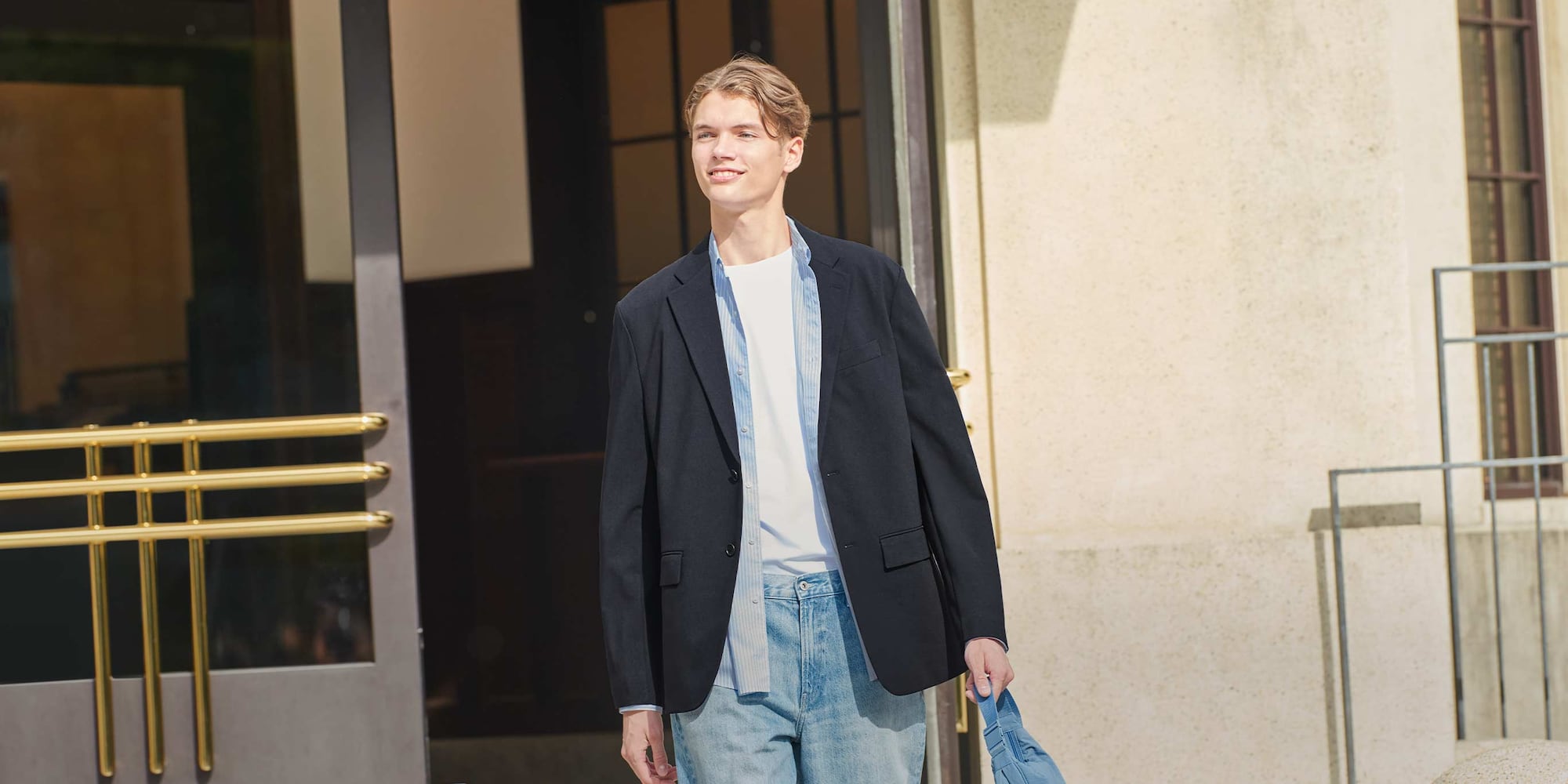 model wearing AirSense Jacket in navy over a light blue striped shirt, white T-shirt and mid wash jeans