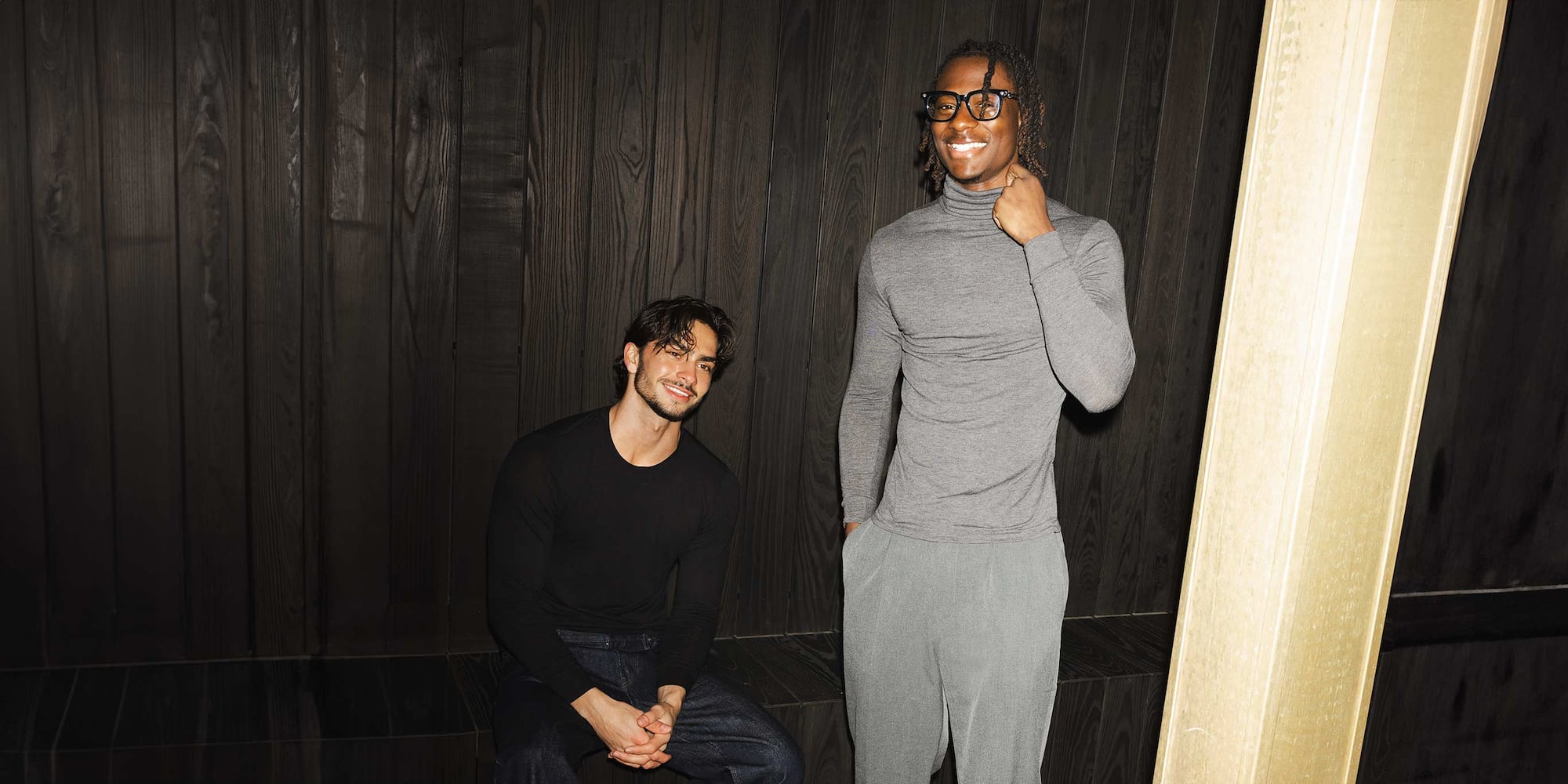 2 models wearing black and grey HEATTECH Cashmere Blend Turtleneck and Crew Neck T-Shirts against a dark wooden background