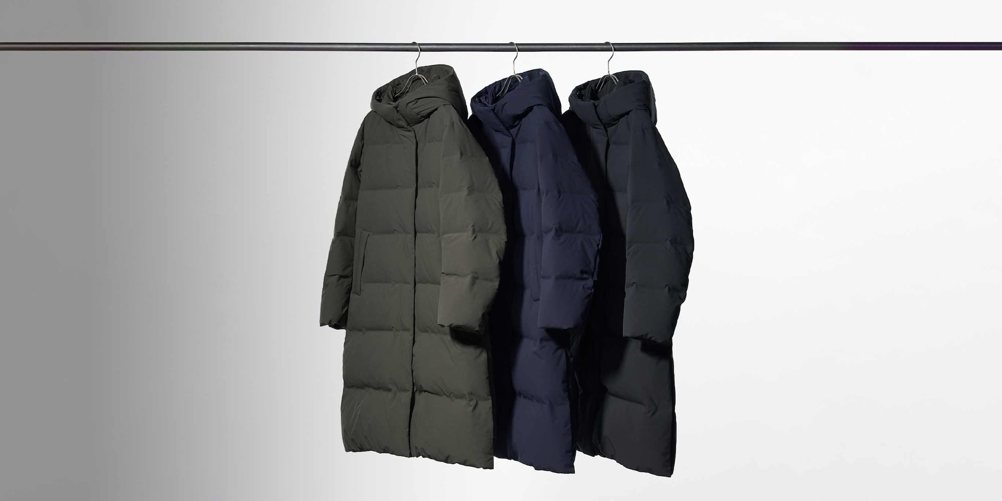 three Seamless Down Long Coats hanging from a rail