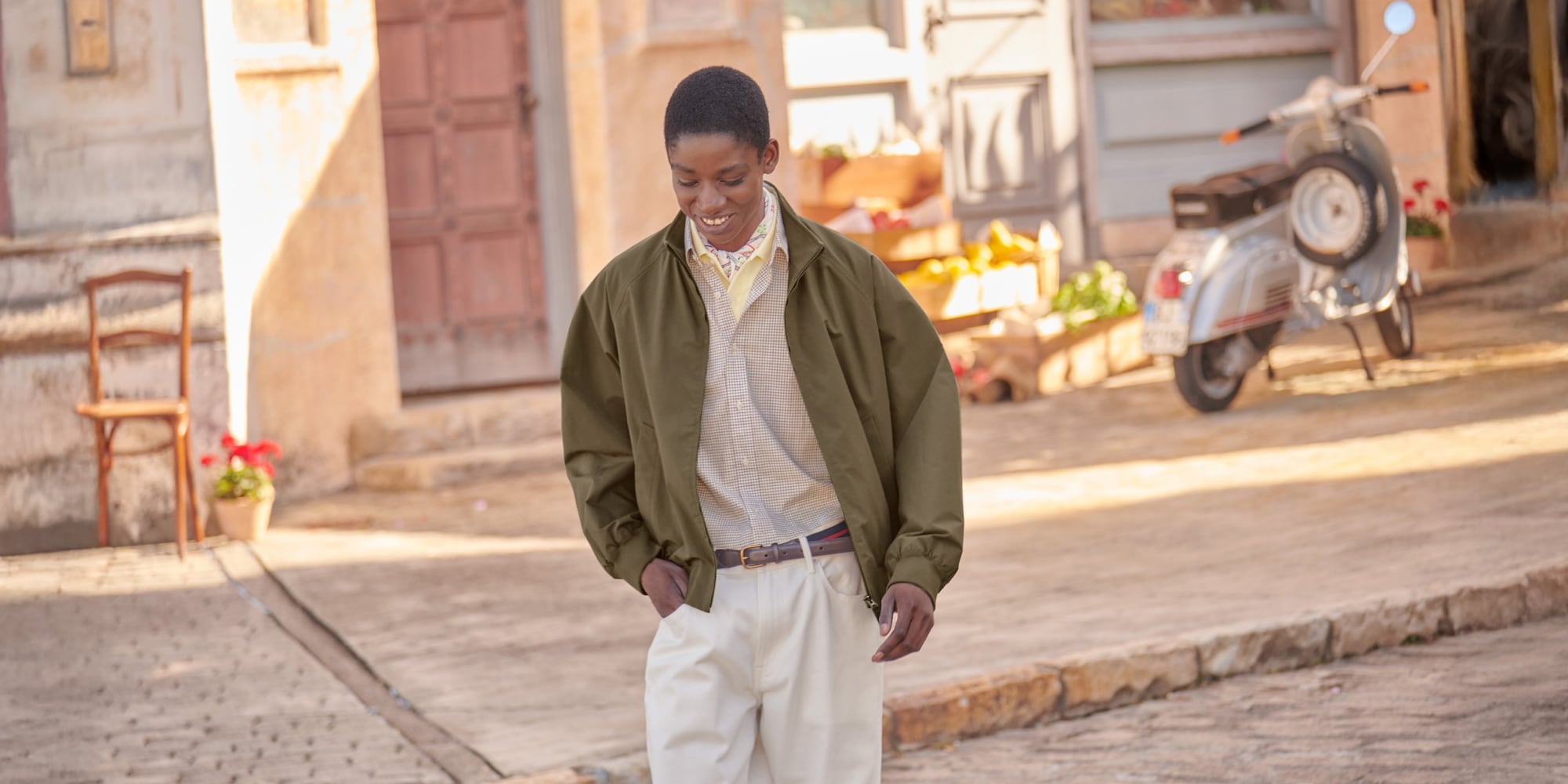 model wearing Harrington Jacket in olive with a beige checked shirt layered over a pale yellow polo and a patterned scarf with chinos and a brown belt
