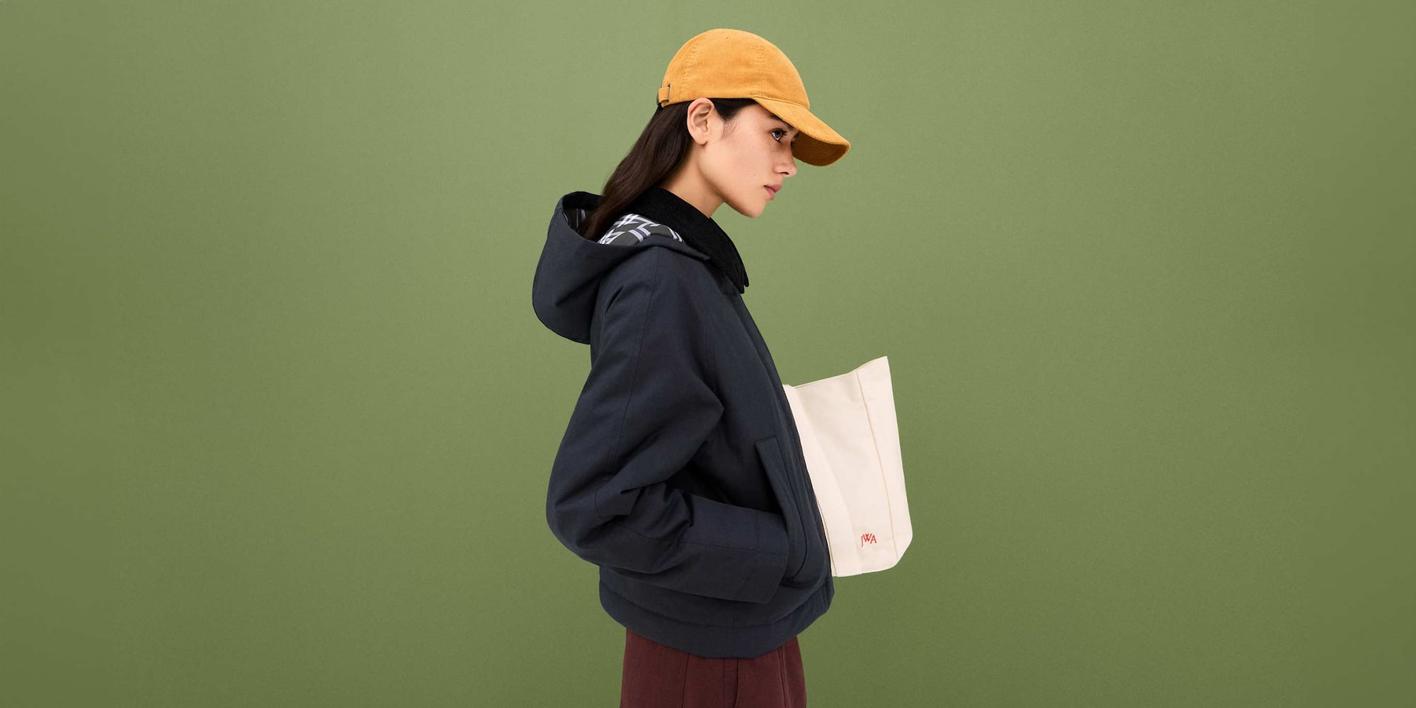 model wearing PUFFERTECH Short Jacket in navy with a yellow cap, carrying a white canvas bag