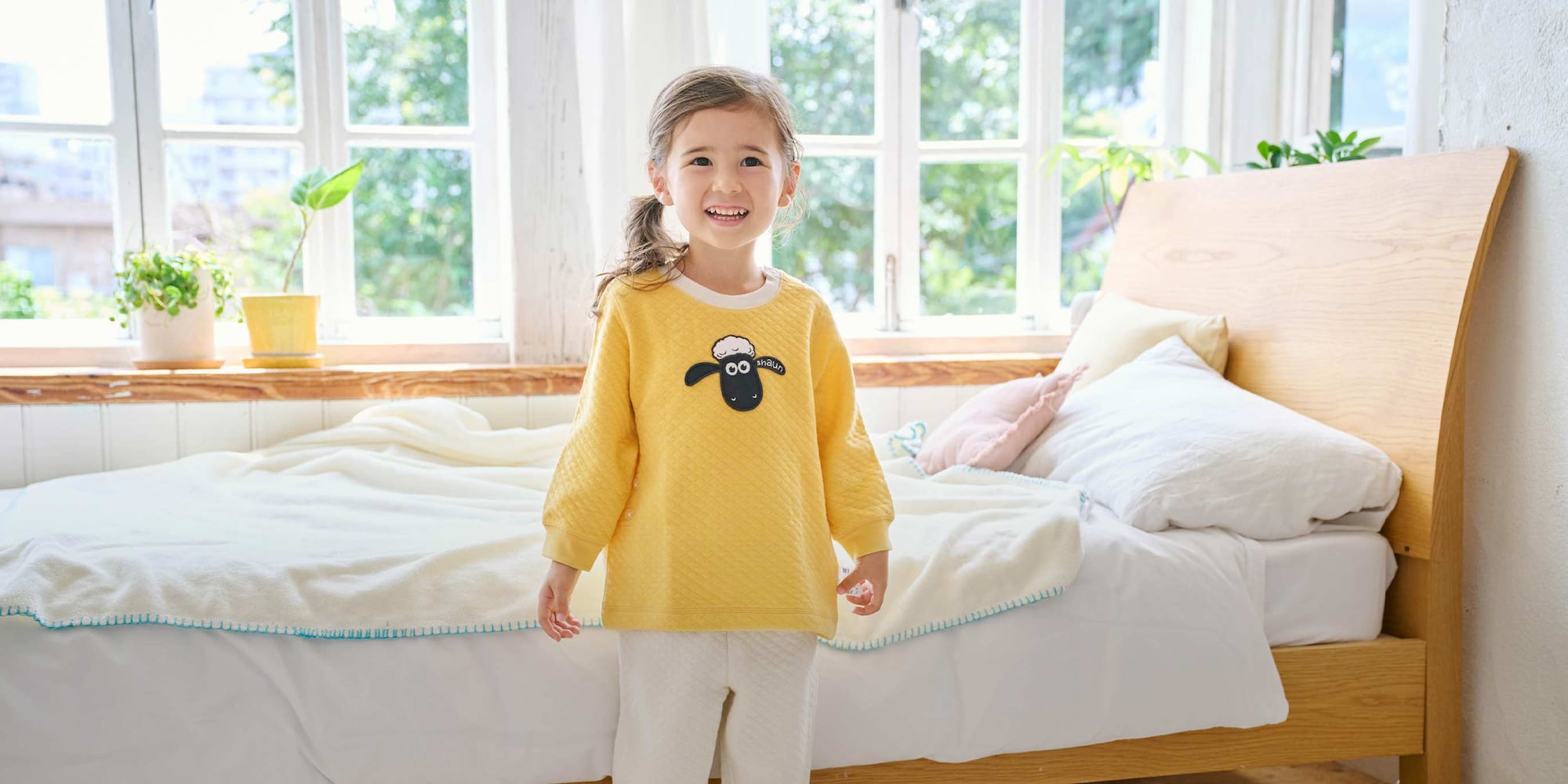 model wearing Clay Animation UT Quilted Pyjamas in yellow with an appliqué design of Shaun the Sheep on the top