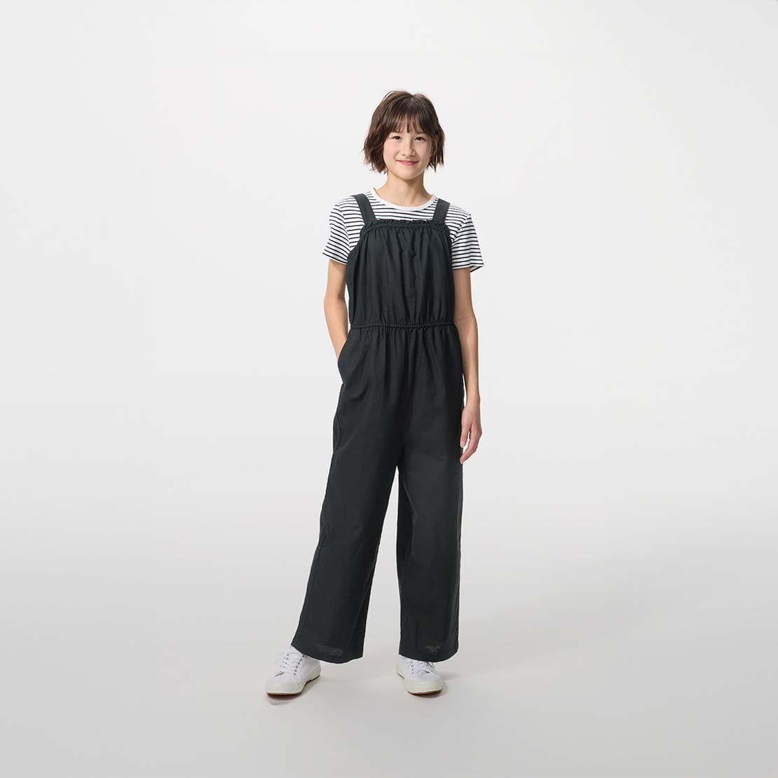 model wearing Linen Blend Jumpsuit in black over a striped T-shirt with white trainers