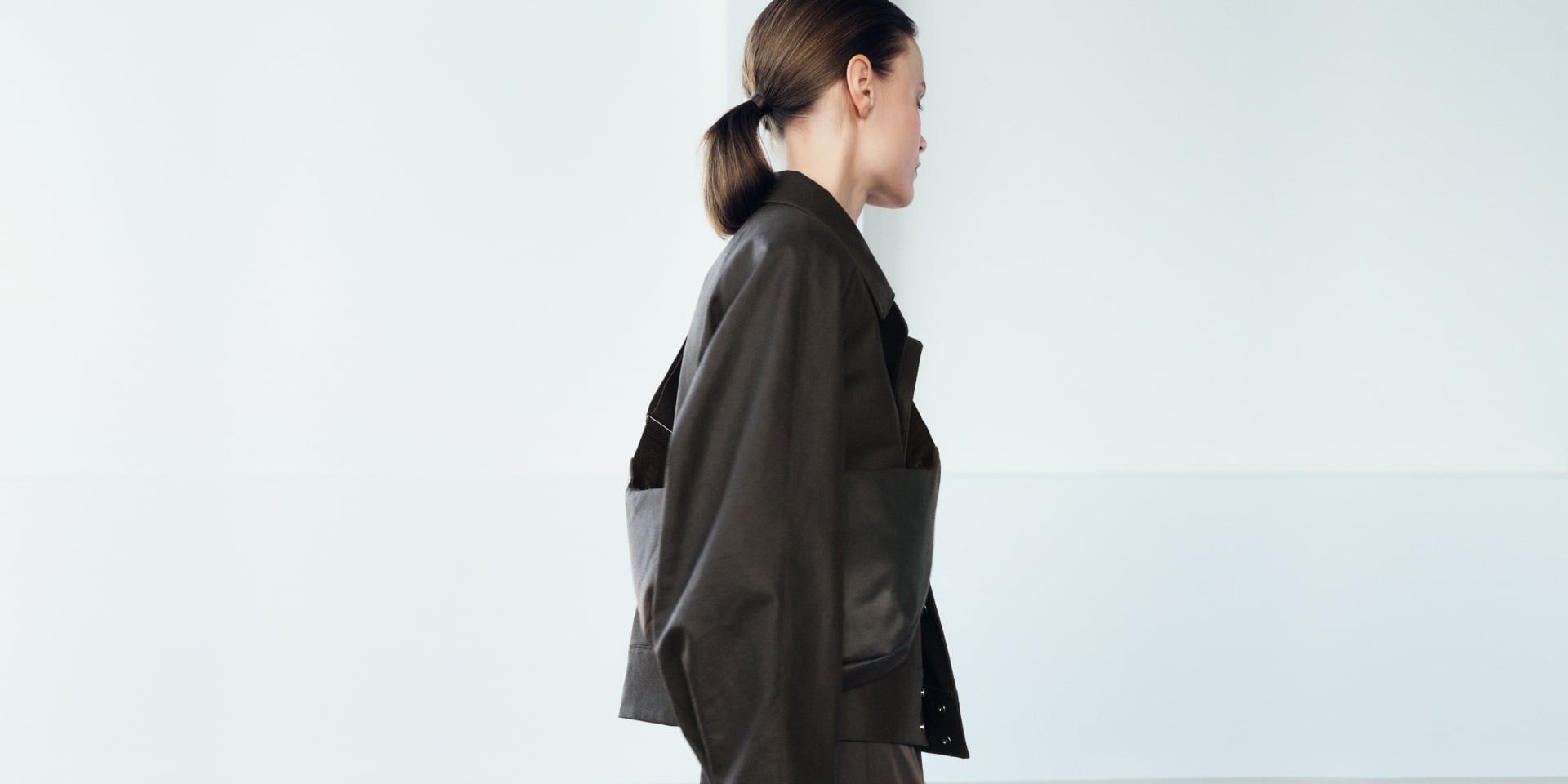 model wearing Coated Blouson in dark brown with a dark brown skirt