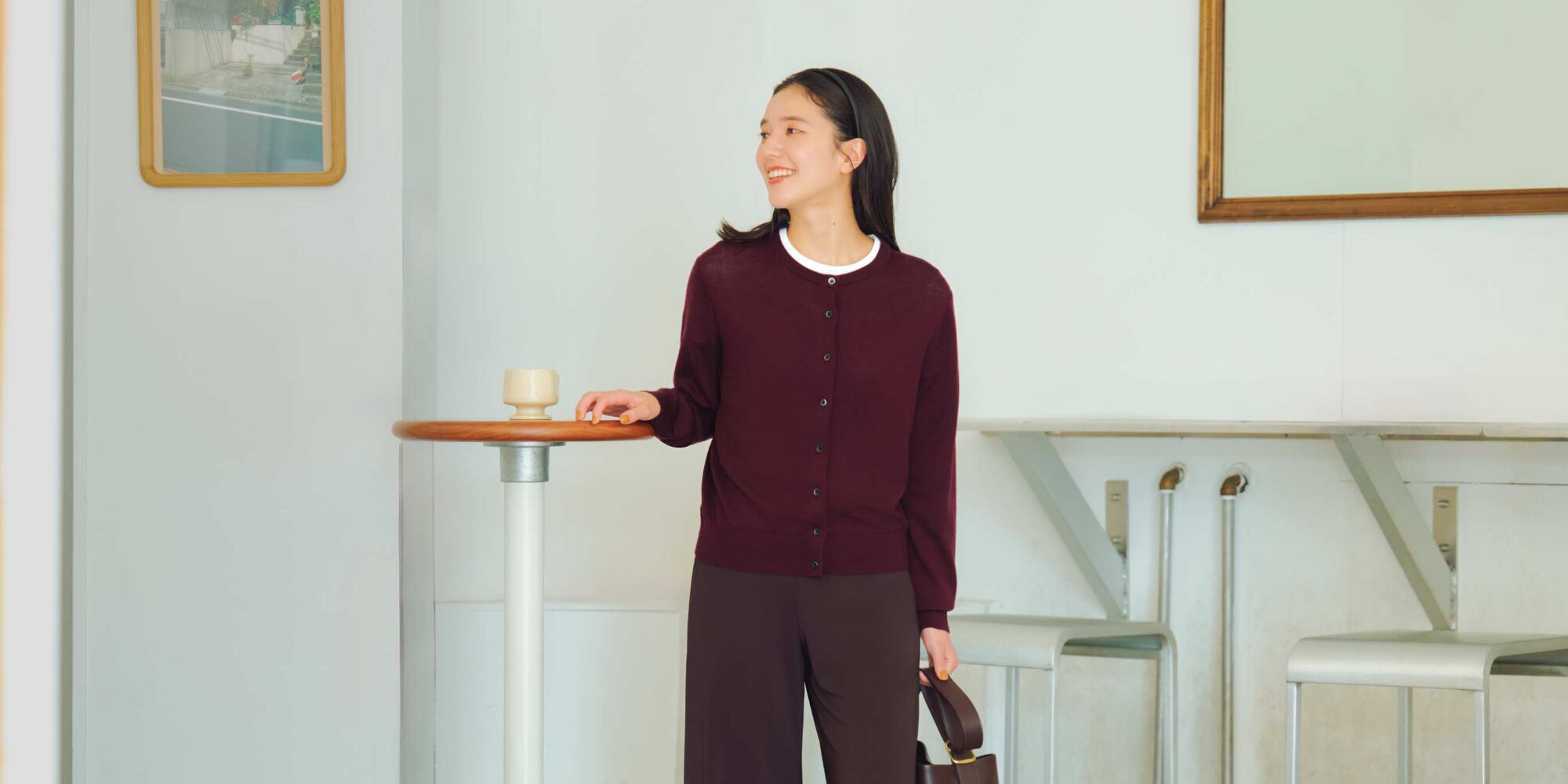 model wearing 100% Merino Crew Neck Cardigan in red over a white T-shirt with wine trousers and handbag