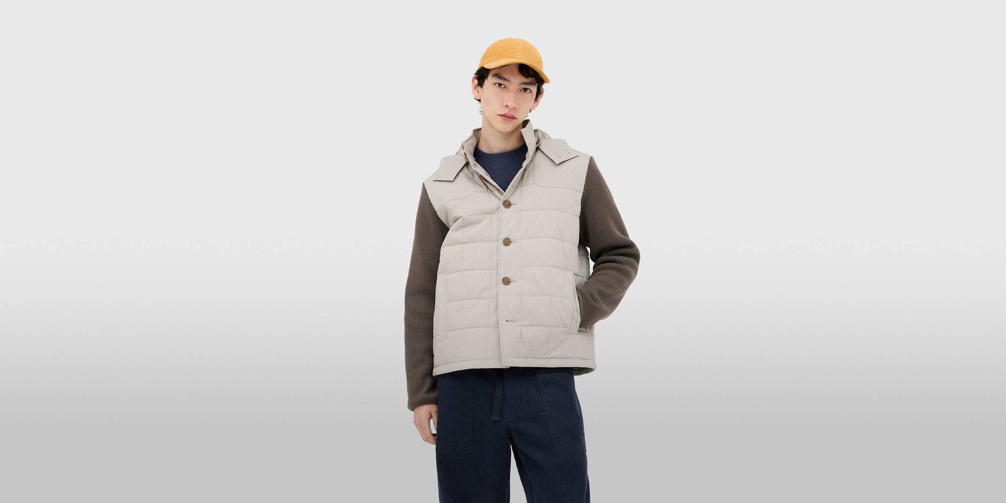model wearing Combination Quilted Jacket in beige with a yellow cap, blue knit and trousers