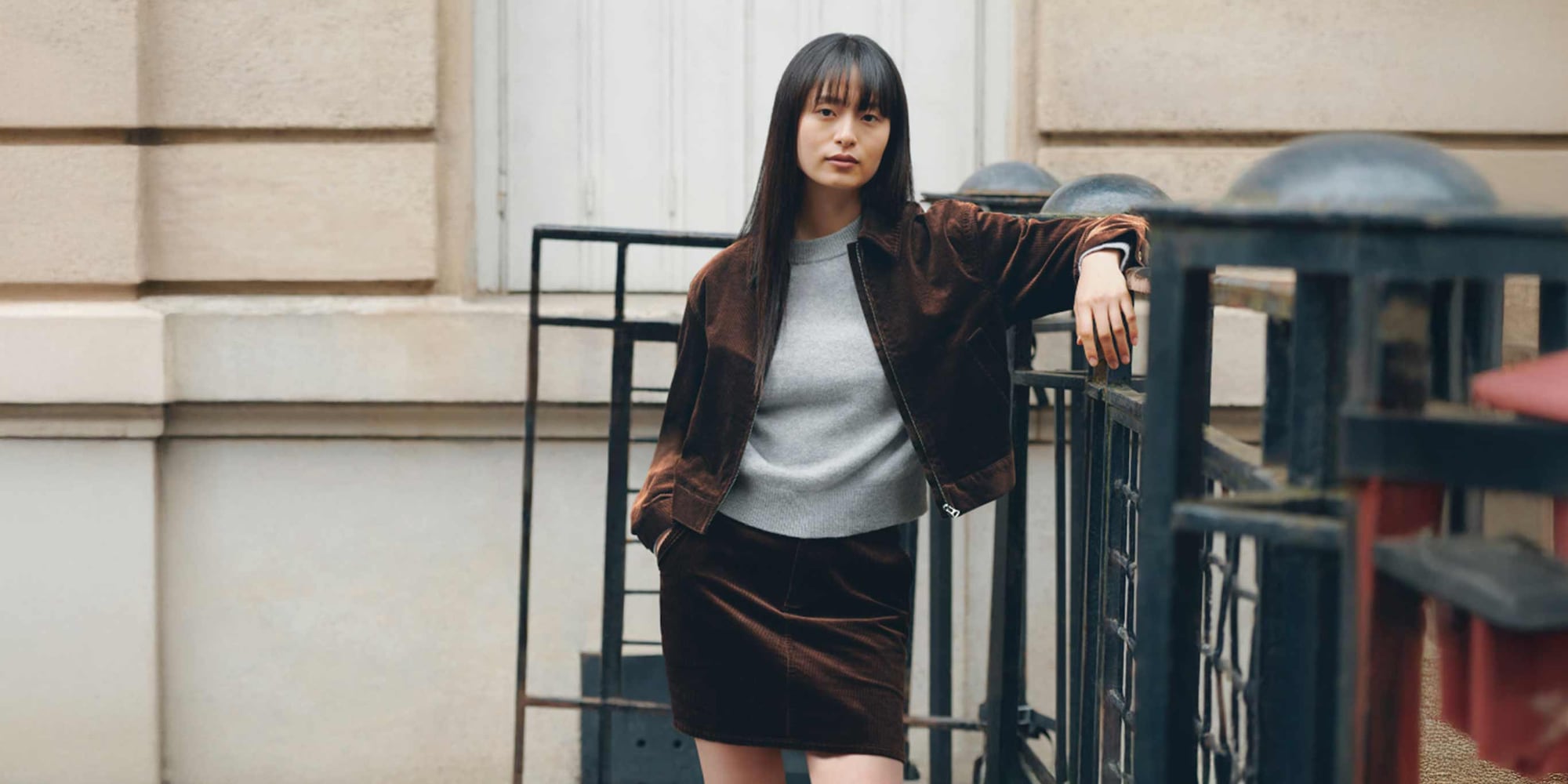 model wearing Corduroy Short Jacket in dark brown with a grey knit and matching skirt