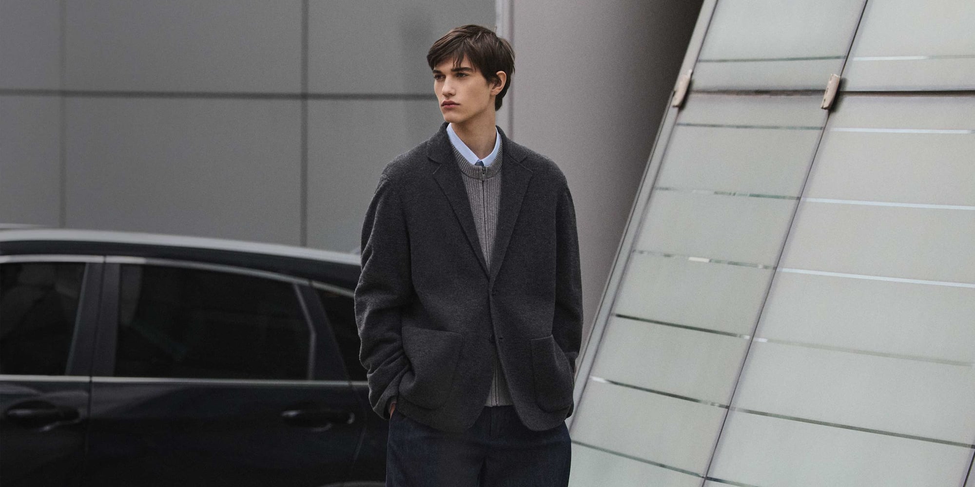 model wearing UNIQLO : C dark grey jacket over a light grey zip-through cardigan and light blue shirt 