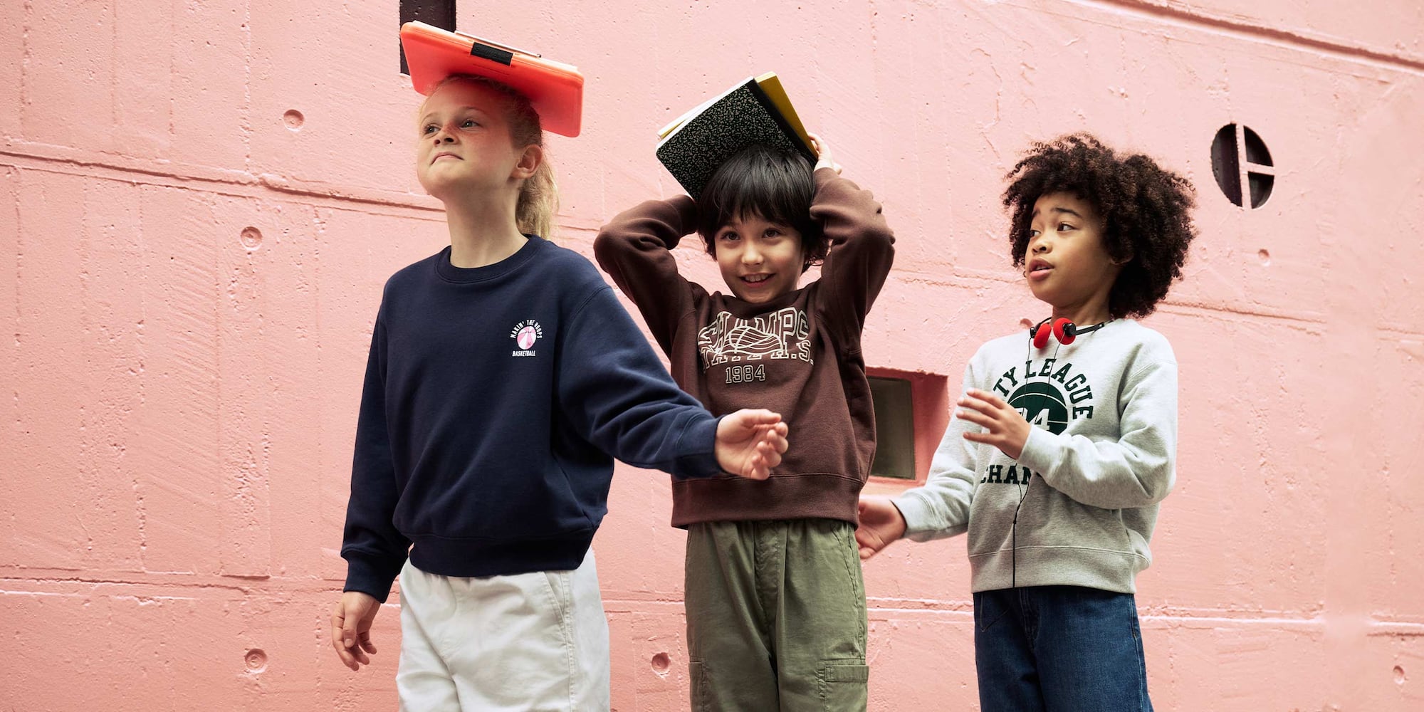 three models wearing graphic sweatshirts in navy, brown and light grey