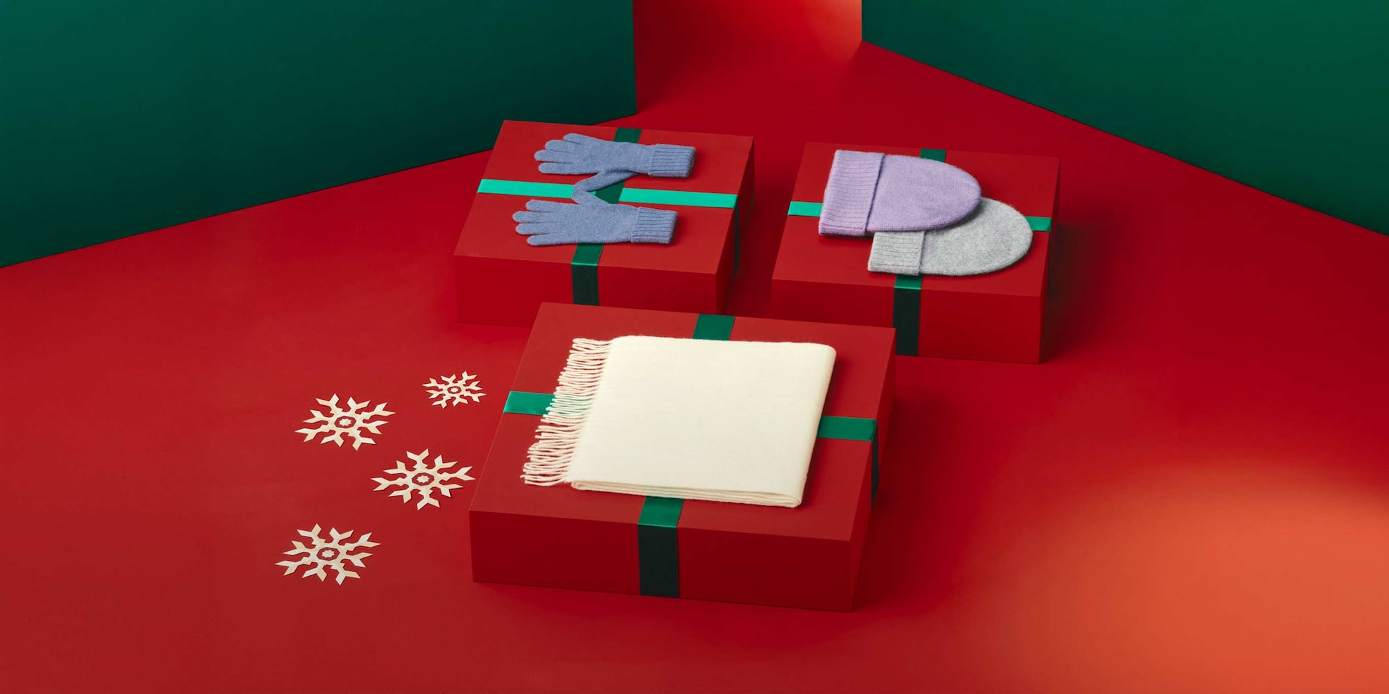 an off-white scarf, hat and gloves arranged with gift boxes