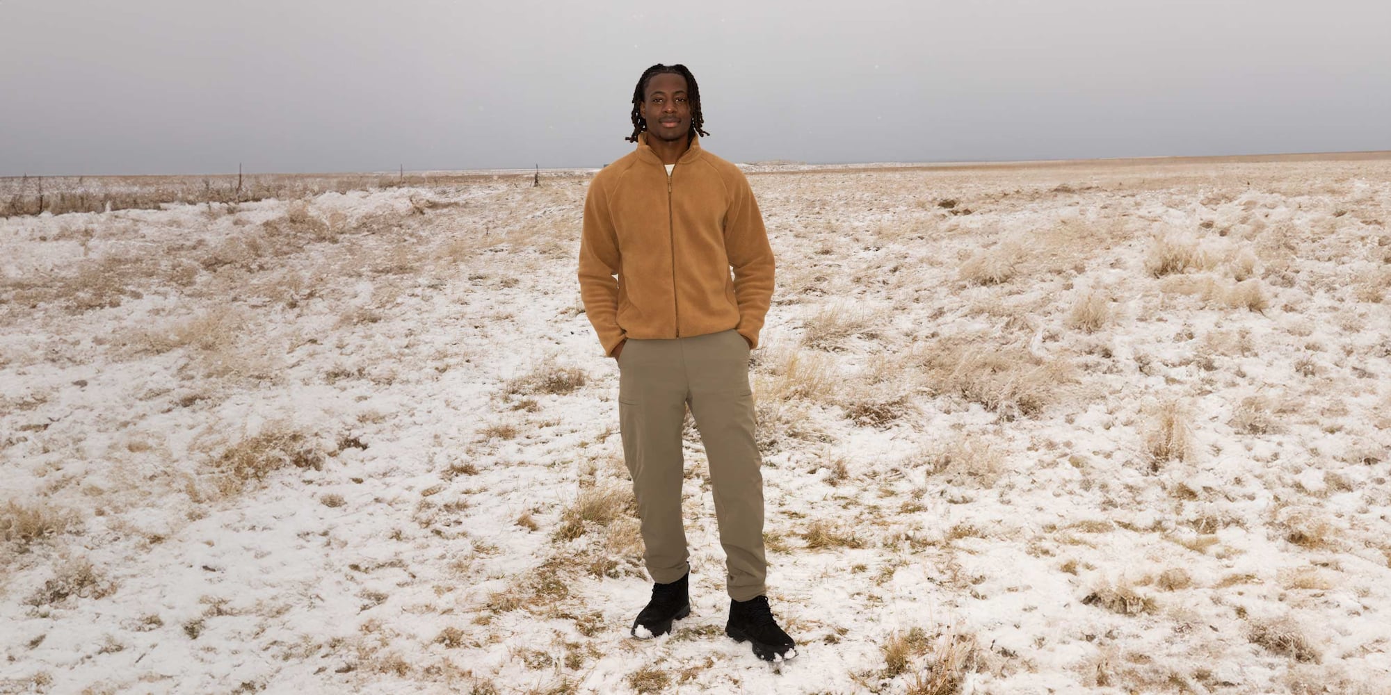 model wearing Warm Lined Trousers in khaki with a beige fleece and black boots while standing in a snowy field