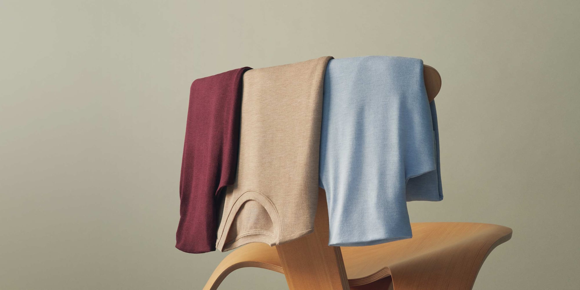 three HEATTECH Extra Warm Cashmere Blend Crew Neck T-Shirts draped over the back of a chair
