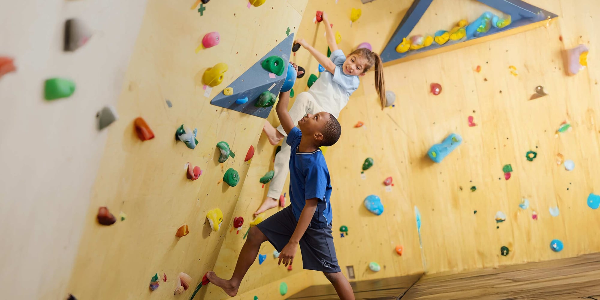 Bimbi con le t-shirt UNIQLO mentre si arrampicano su una parete da arrampicata