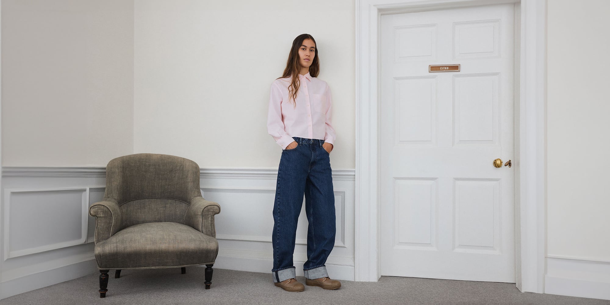 model wearing a pink shirt with baggy jeans in blue and brown shoes