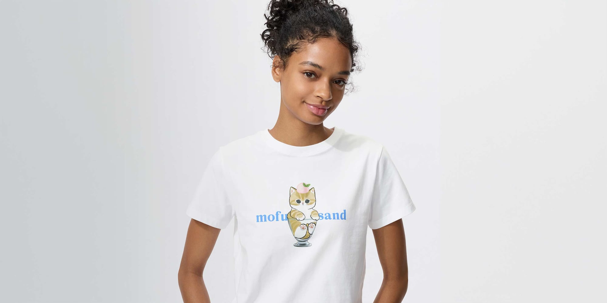 model wearing mofusand UT Graphic T-Shirt in white, featuring a mofusand cat sitting in an ice cream glass with a scoop of pink ice cream and a mint leaf on its head