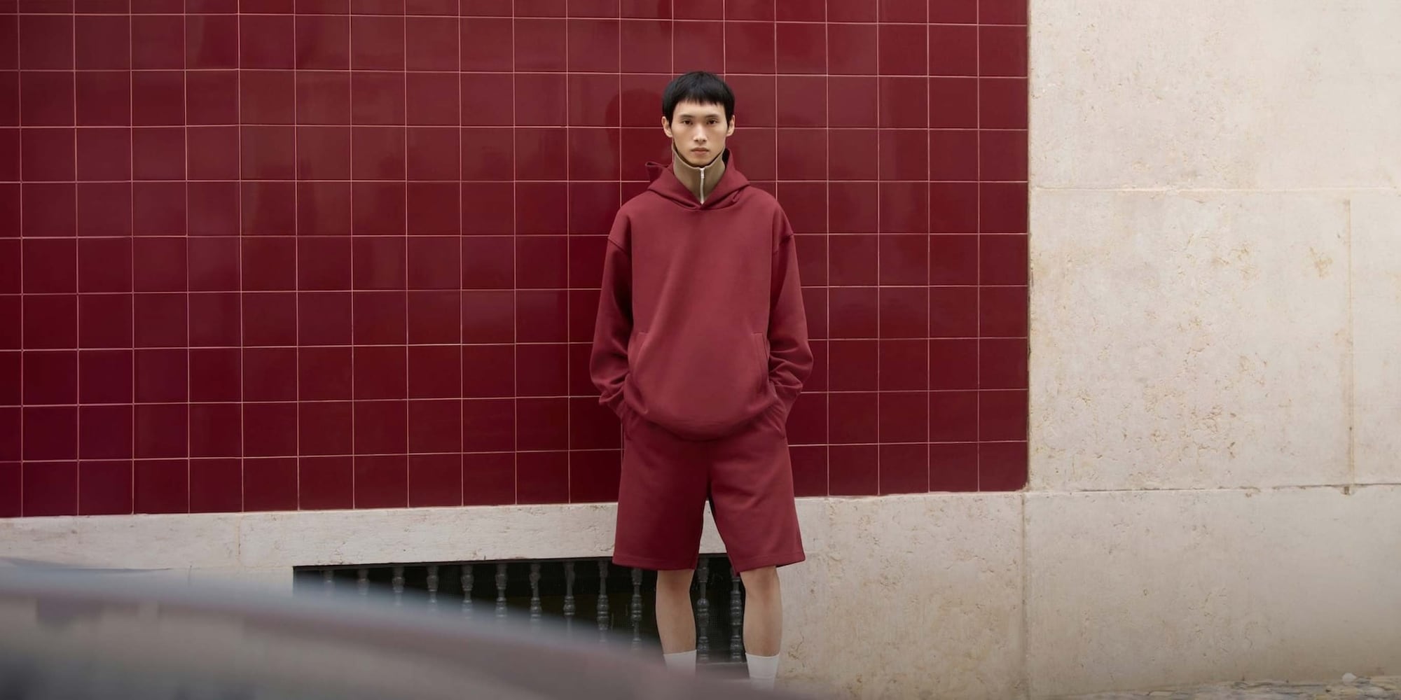 model wearing oversized pullover hoodie and matching shorts in wine over a brown zip-through funnel neck top and white socks