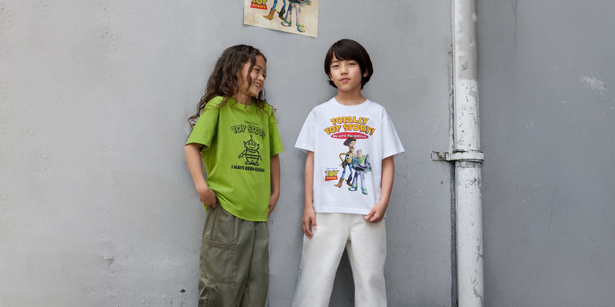 models wearing TOY STORY 30th UT Graphic T-Shirts; one green featuring one of the aliends with the words i have been chosen! one featuring Woody and Buzz and the words totally toy story! new world. new adventure