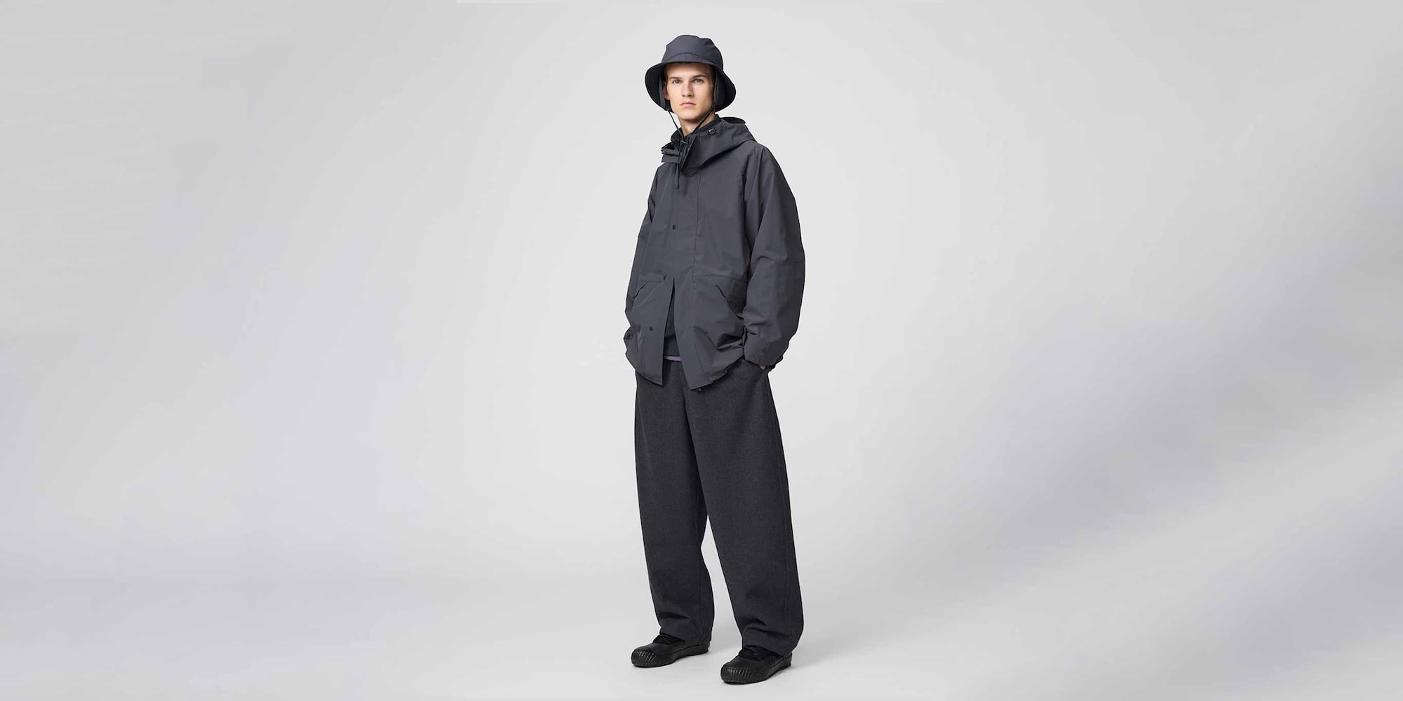 model wearing Brushed Sweat Wide Trousers in dark grey with a dark grey bucket hat and jacket and black shoes
