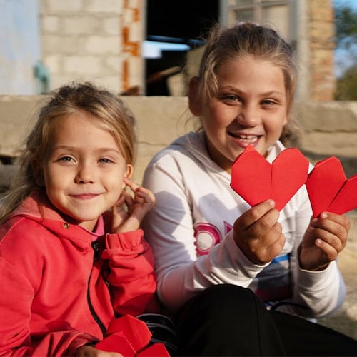 two children holding origami hearts