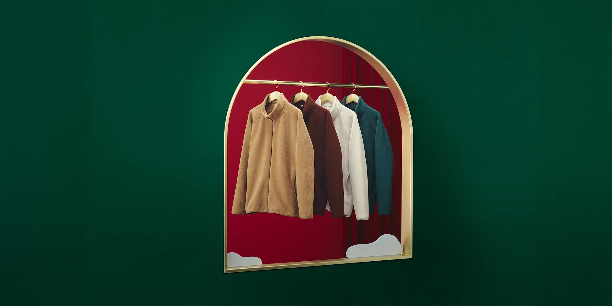 four UNIQLO fleece jackets hanging on a gold rail against a red and green background