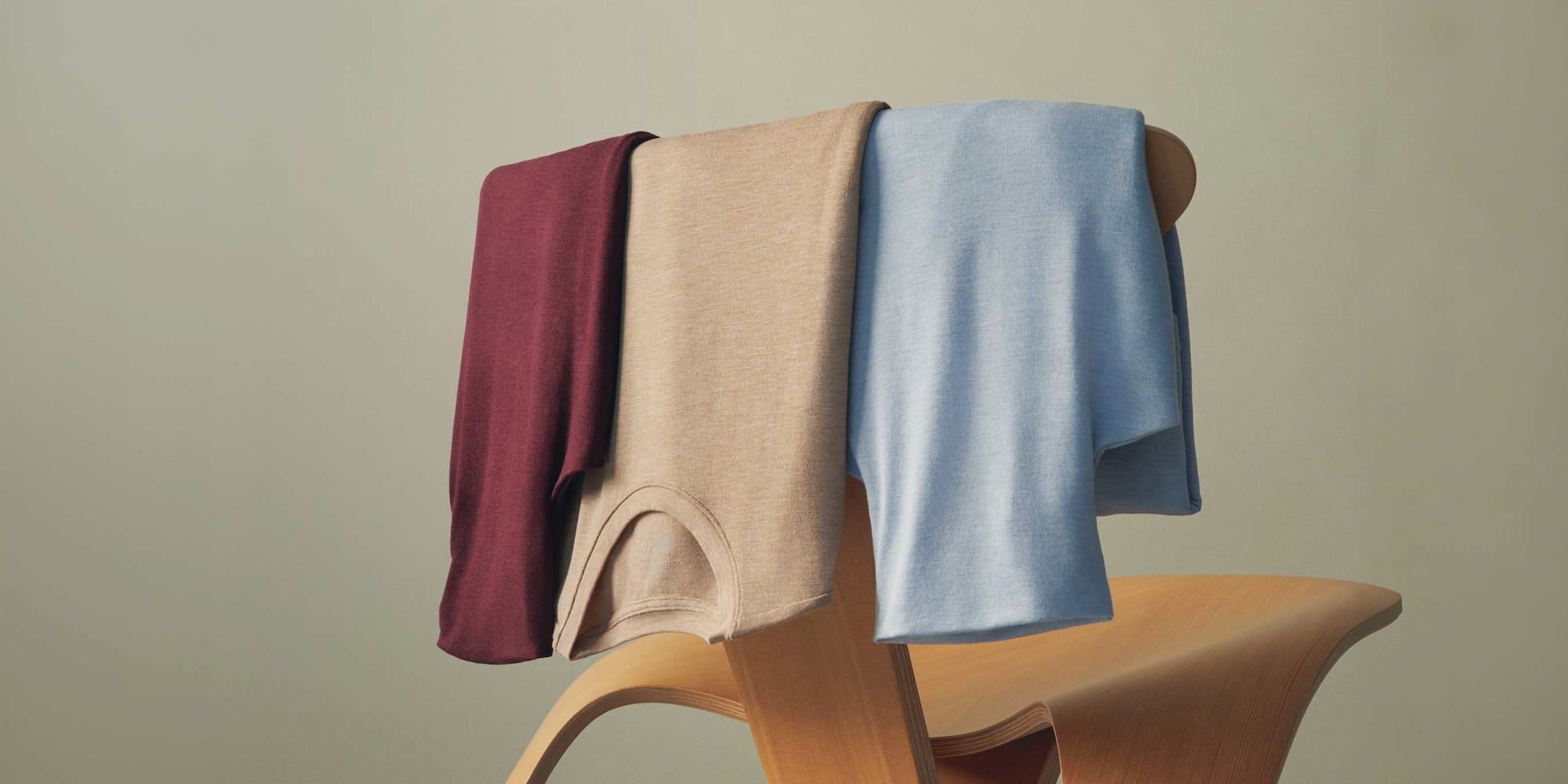 three HEATTECH Extra Warm Cashmere Blend Crew Neck T-Shirts draped over the back of a chair