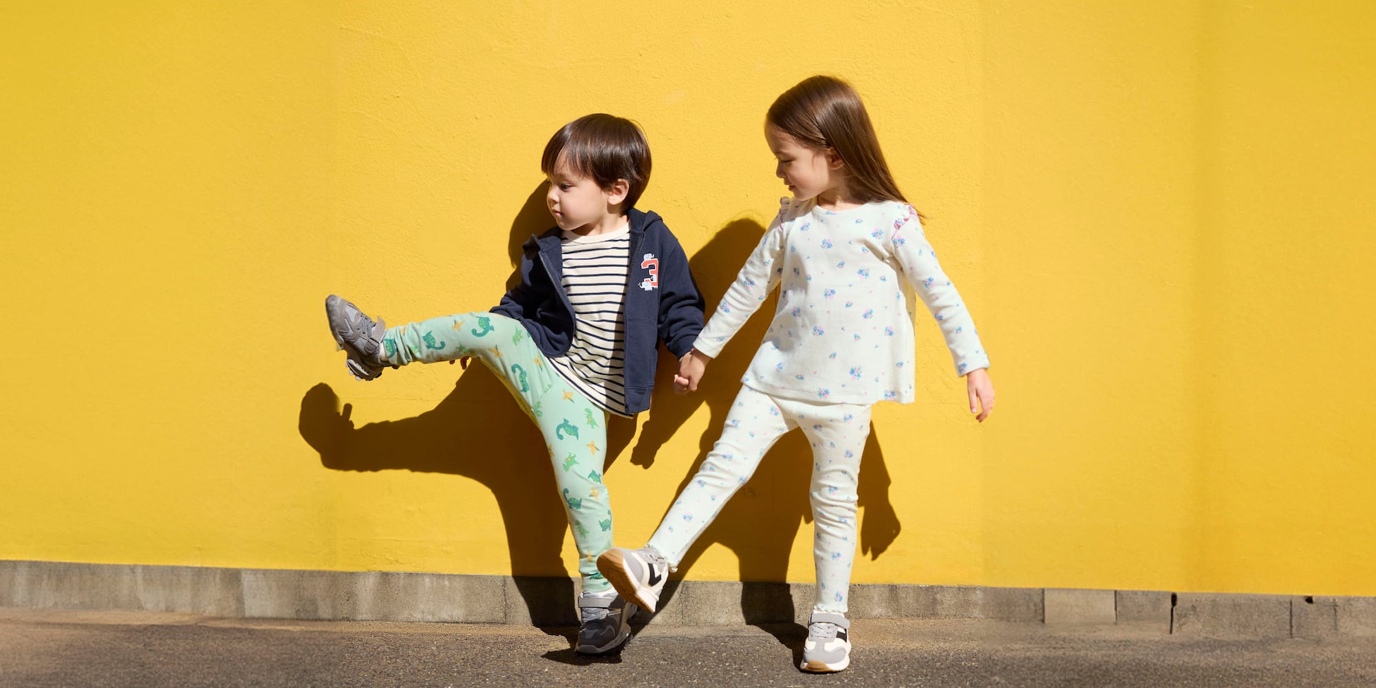 two models wearing UNIQLO printed leggings, each lifting one leg to the side