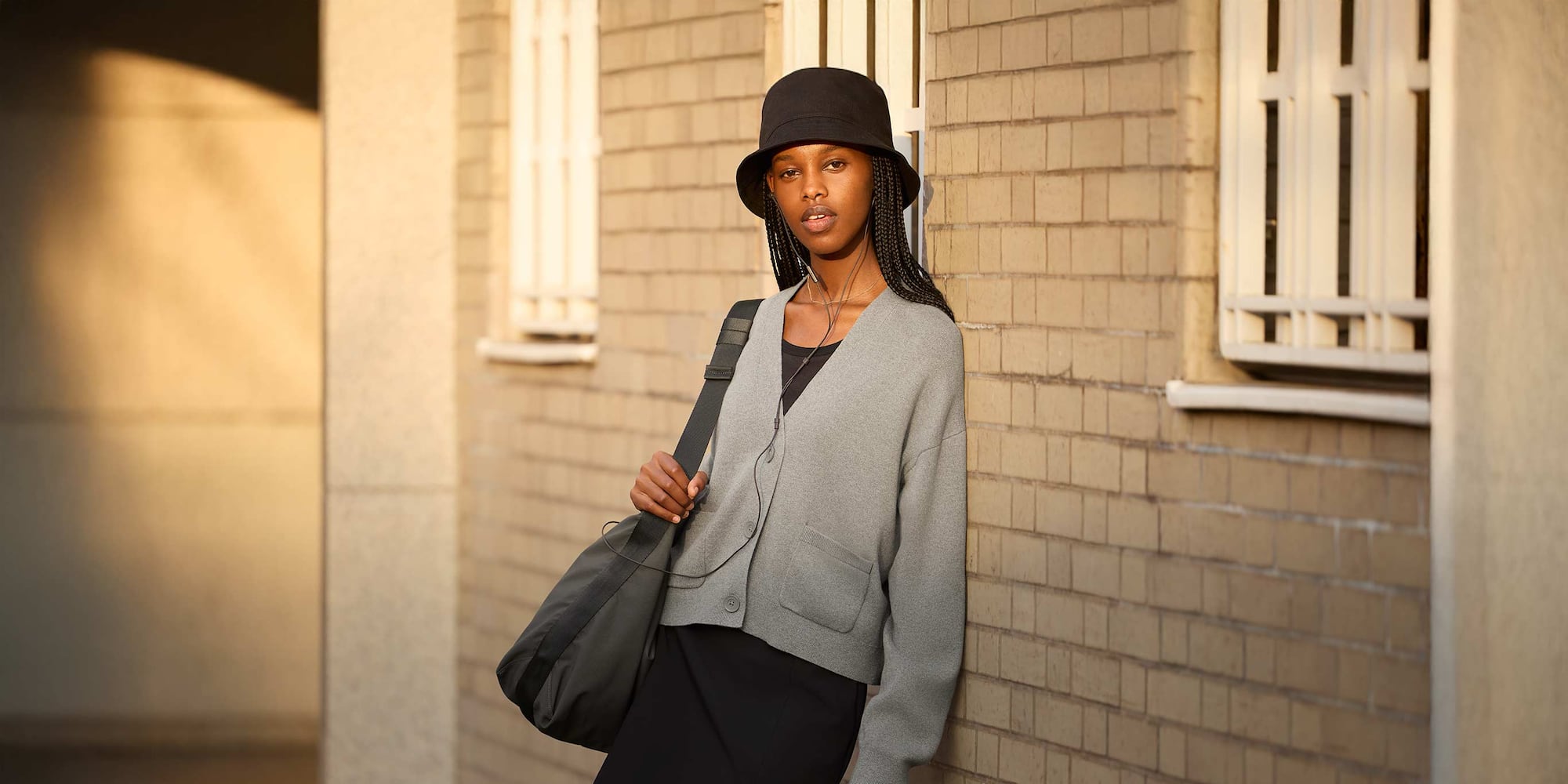 model wearing Smooth Cotton V Neck Cardigan in grey over a black scoop neck top with a black bucket hat