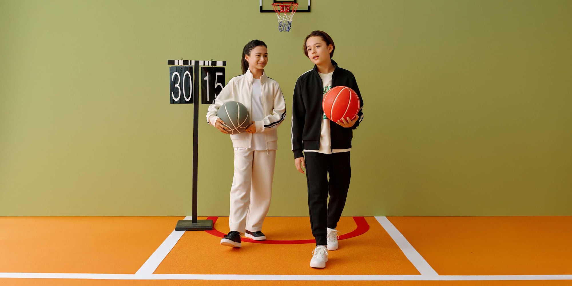 les mannequins portent la collection de sport UNIQLO sur un terrain, en portant des balles de basket