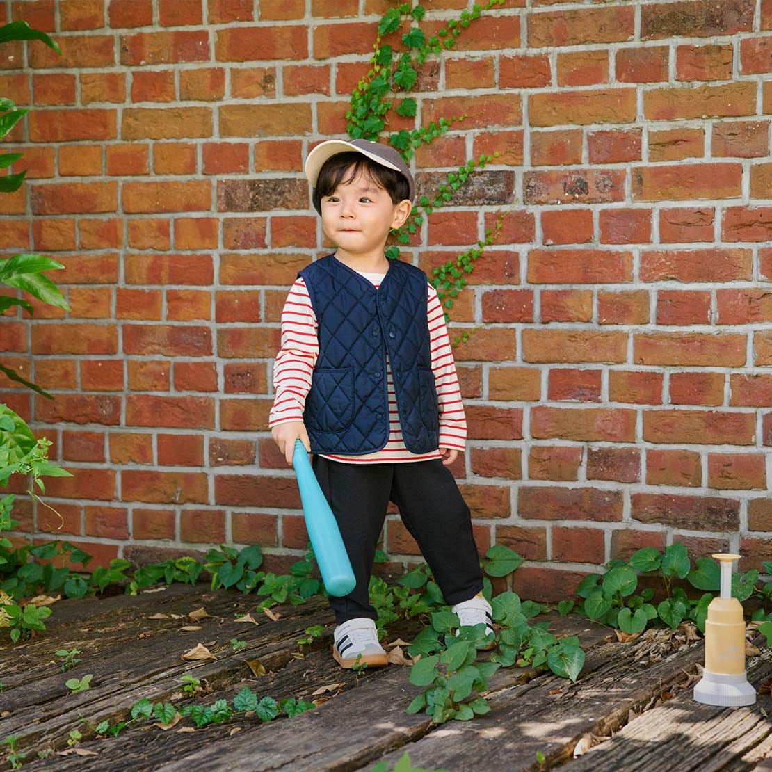 bambino che indossa un gilet trapuntato blu navy con maglia a maniche lunghe a righe rosse e bianche, berretto e pantaloni blu navy