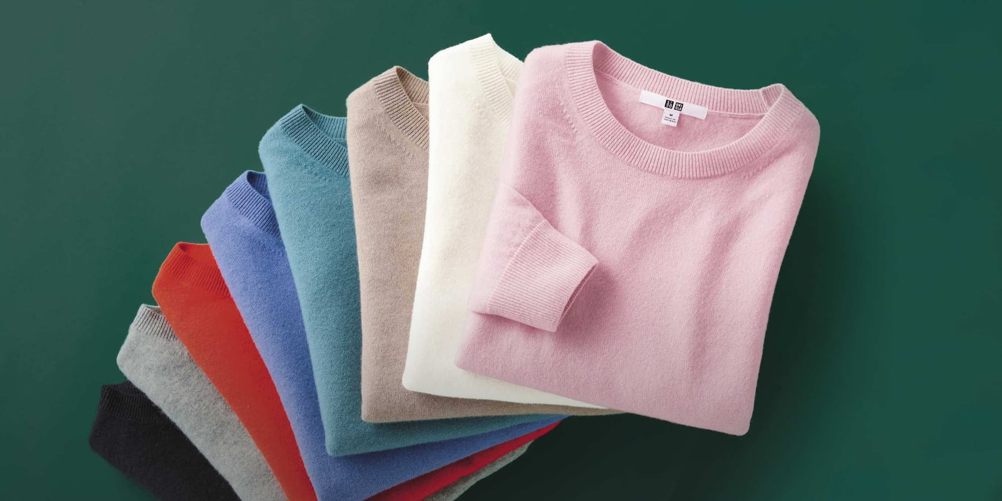 pile of folded 100% cashmere crew neck jumpers in different colours